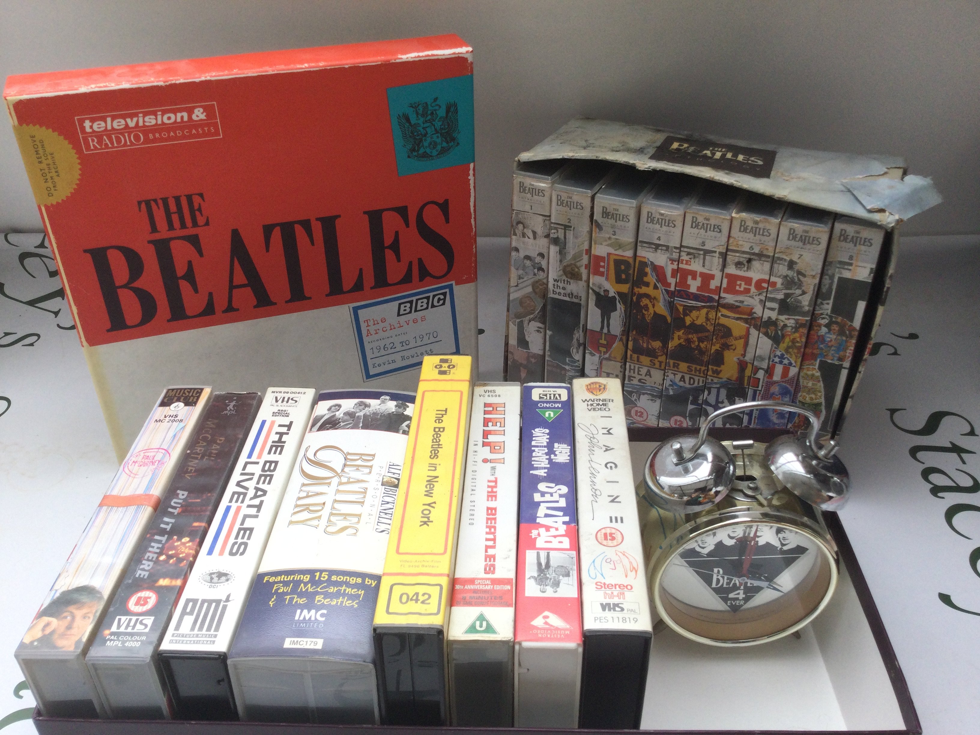 A Beatles 'Archives' book by Kevin Howlett, VHS tapes and a Beatles alarm clock.
