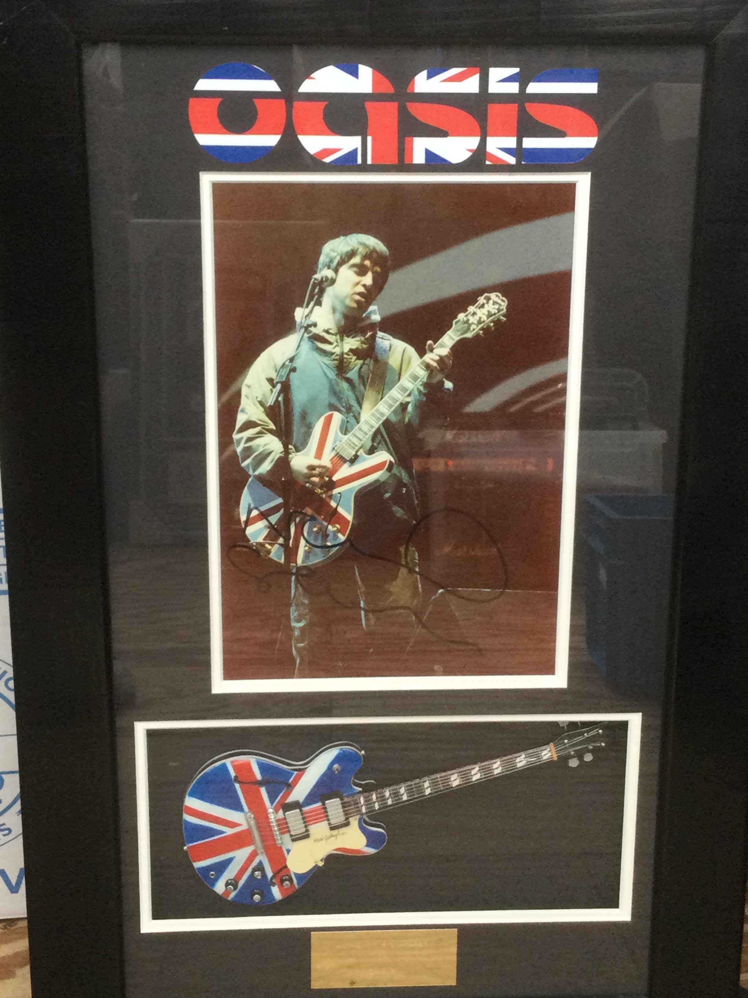 A framed and glazed Oasis display signed by Noel Gallagher, approx 68cm x 43cm.