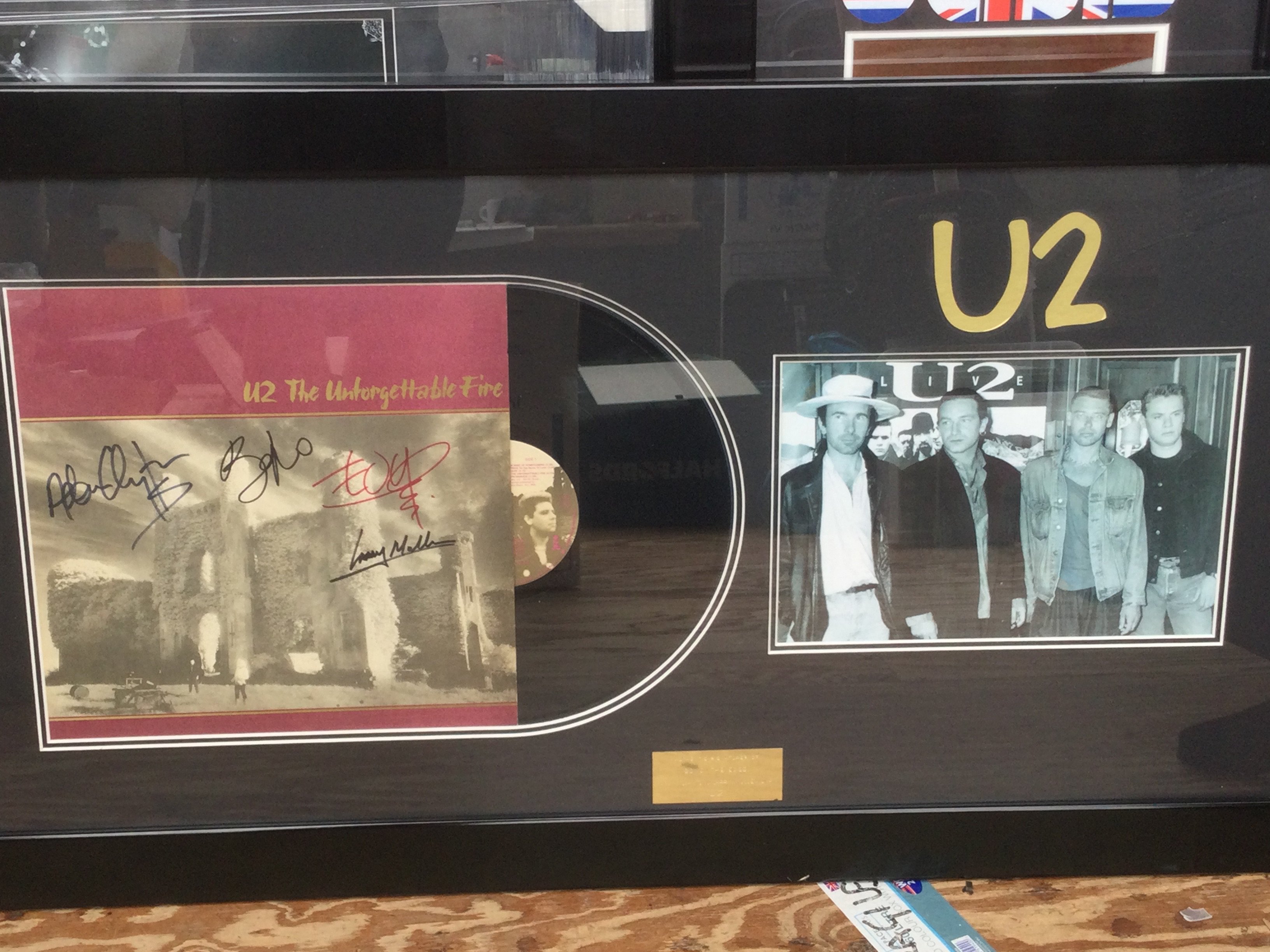 A framed and glazed U2 display signed by all band members with COA, approx 55cm x 100cm.