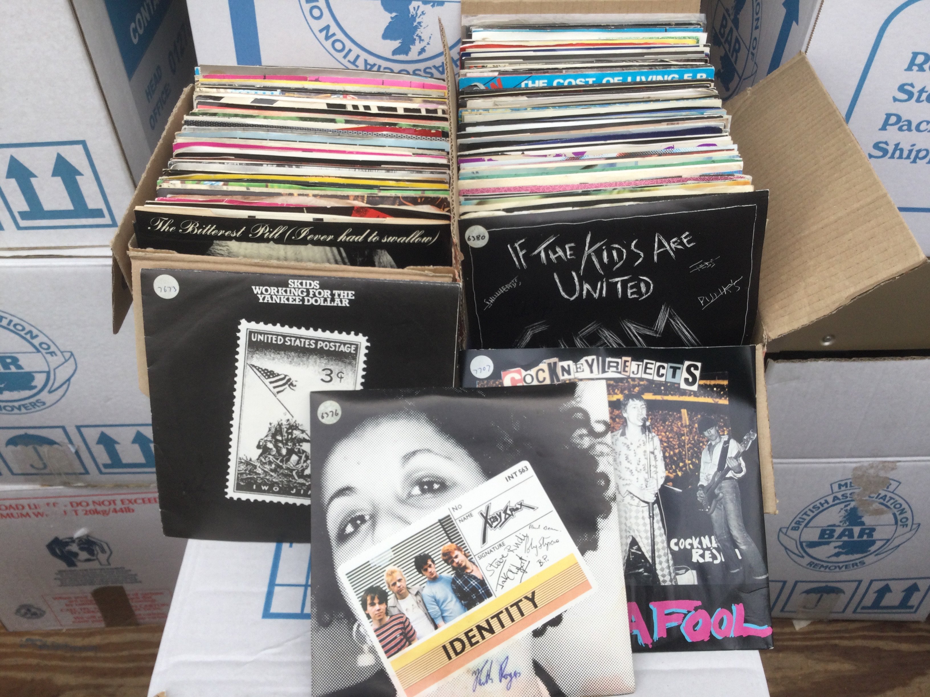 Three small boxes and a record case of punk, post punk and heavy rock 7" singles and EPs including some promos.