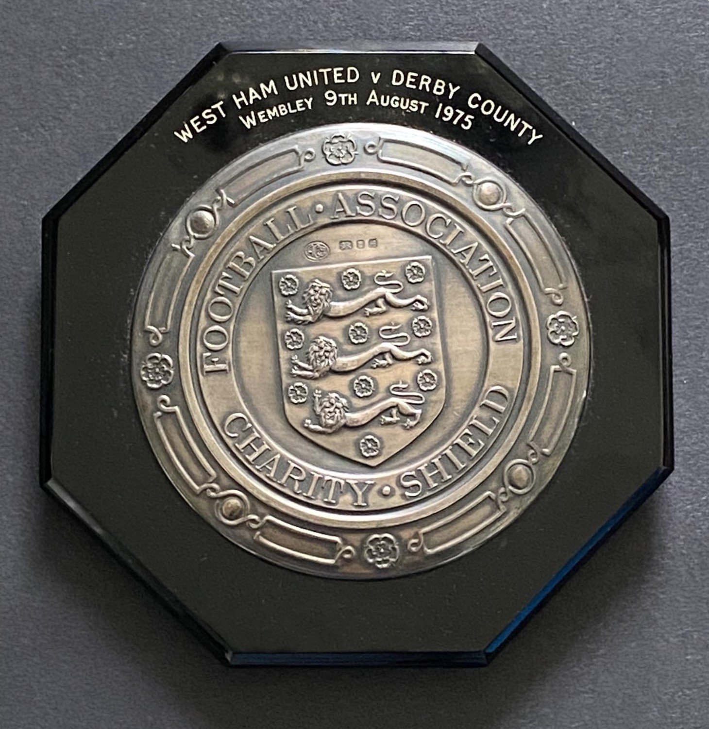 1975 Charity Shield Plaque West Ham v Derby: Superb item awarded to manager John Lyall with match details to surrounding. The inner silver coloured plaque has the words Football Association Charity Shield around the 3 lions emblem. Slight damage. COA from family.