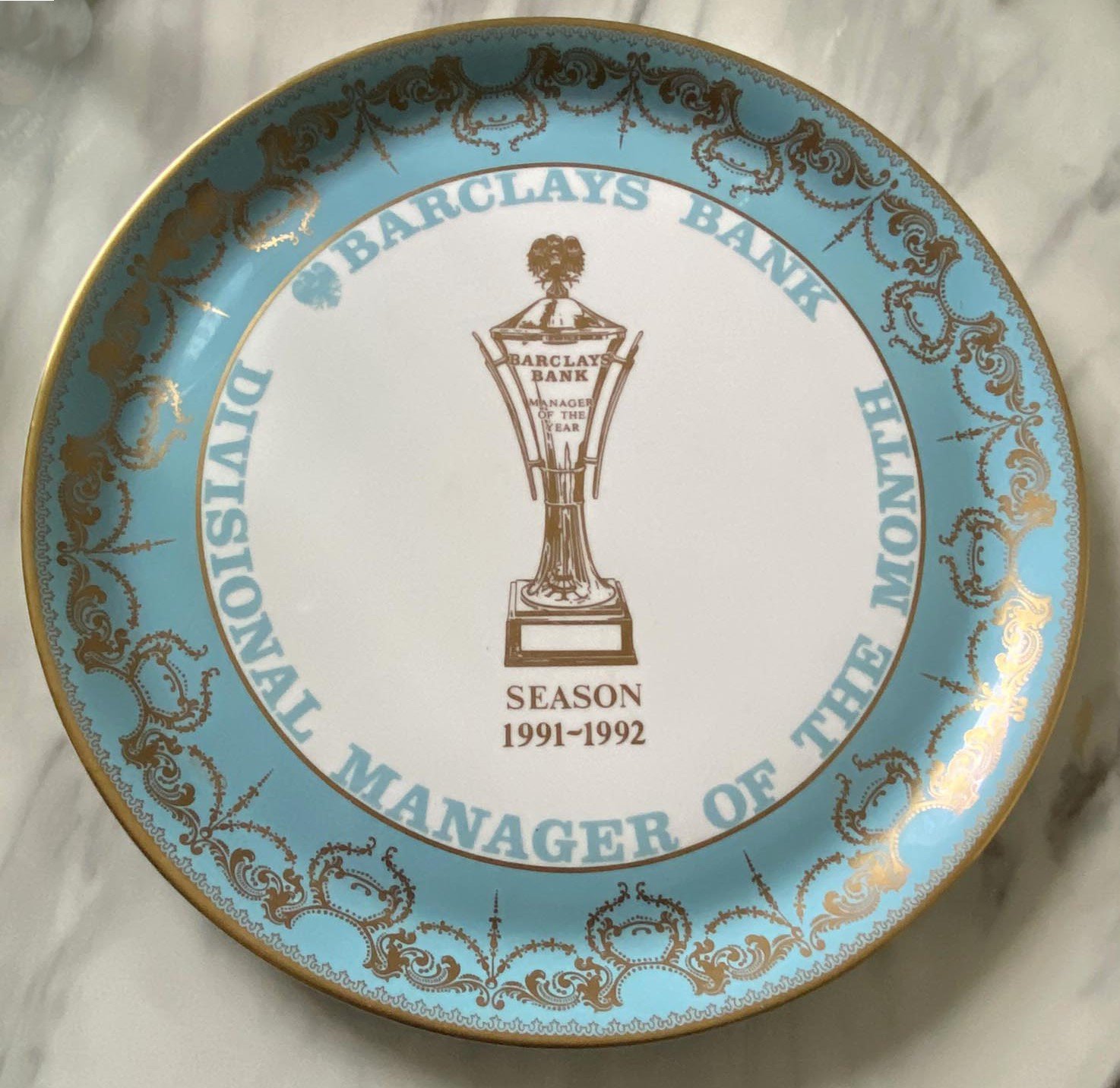 John Lyall Ipswich Town 91/92 Manager Of The Month Award: Aynesley China plate which states Barclays Bank Divisional Manager Of The Month. This was awarded for February 1992 in the season that Ipswich won league division 2. Photo included of Lyall with champagne and another in his office both signed by him. (Champagne not present)