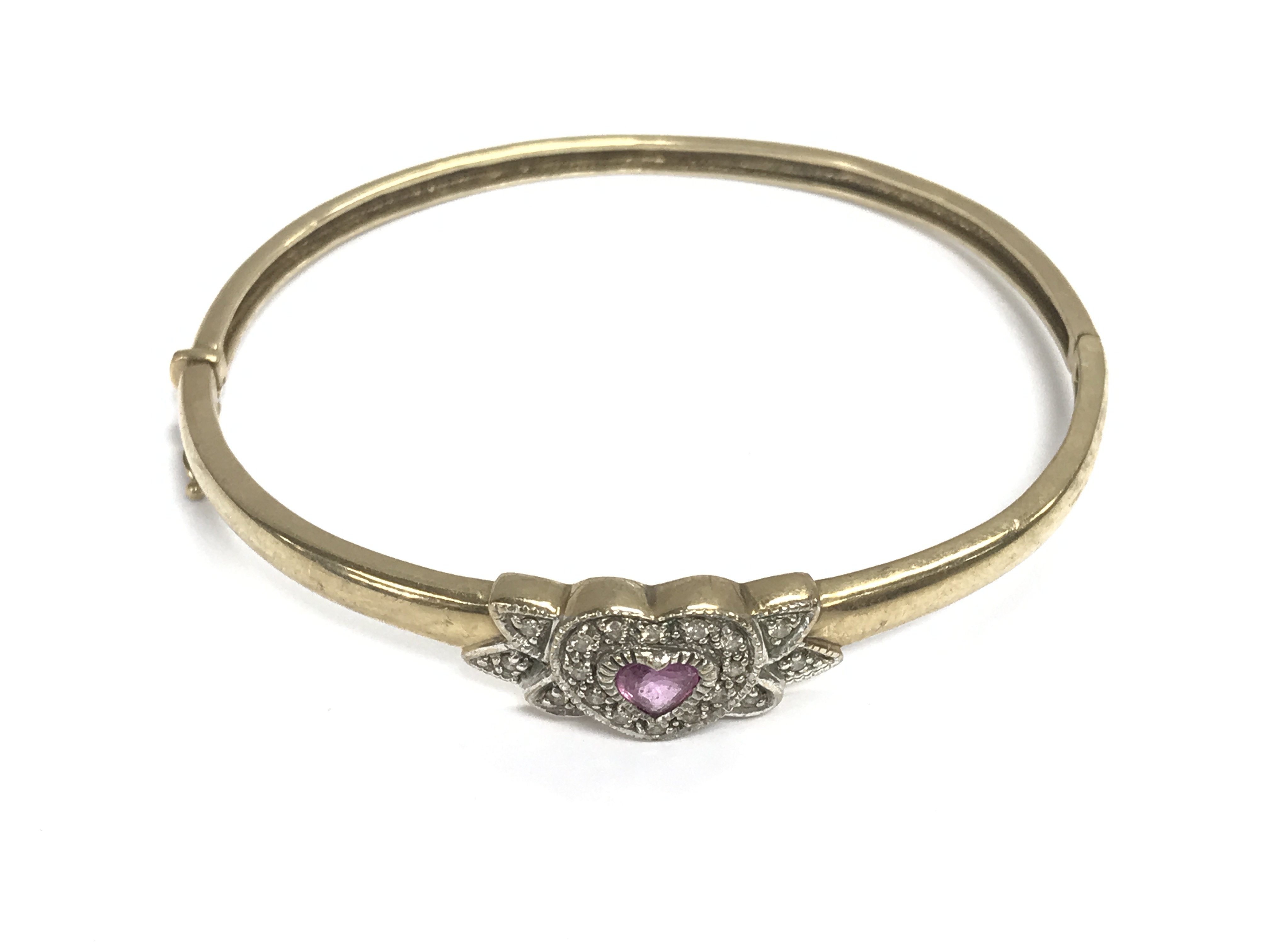 A 9ct gold bangle with a Ruby heart. 10.98g and 6.5cm diameter