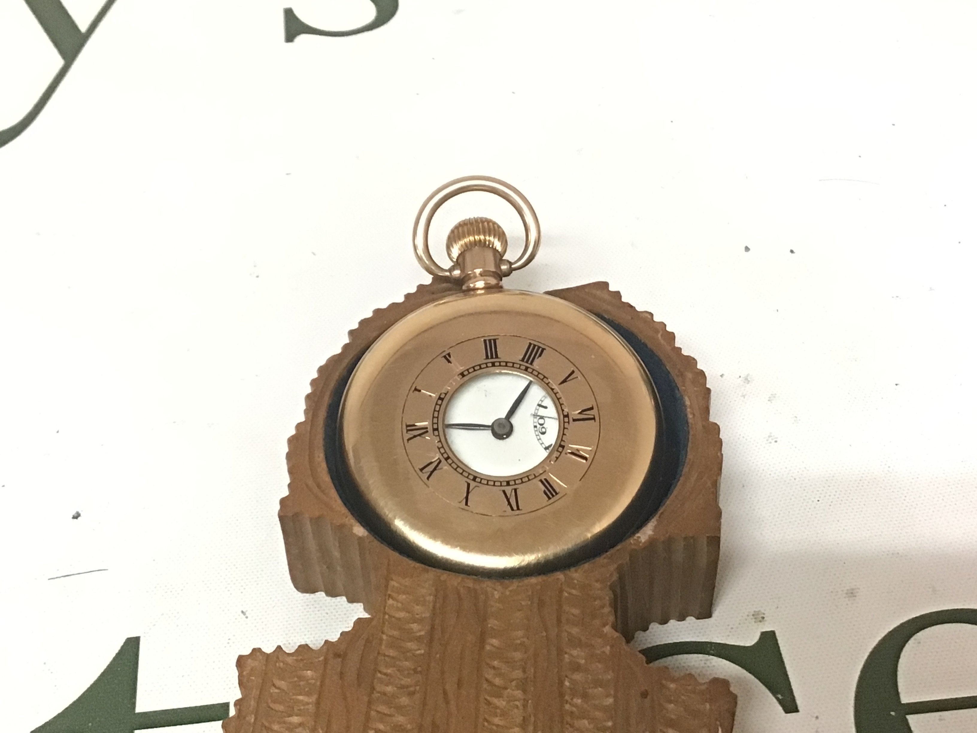 A gold plated half hunter pocket watch button wind seen working.in a carved wood Swiss watch case