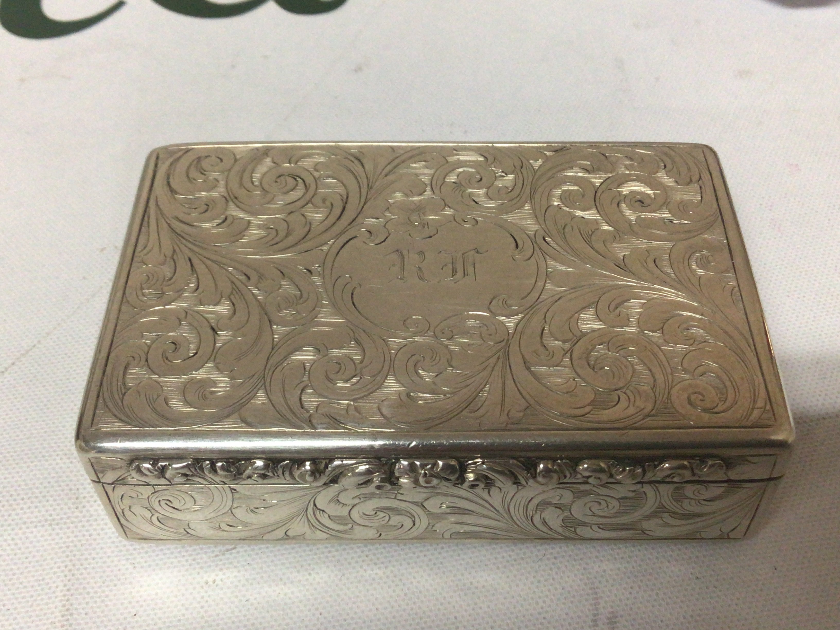 A Victorian Silver snuff box of rectangular shape with elaborate scroll decoration parcel gilt interior makers mark ES Birmingham hallmarks. 7cmx4.5cm