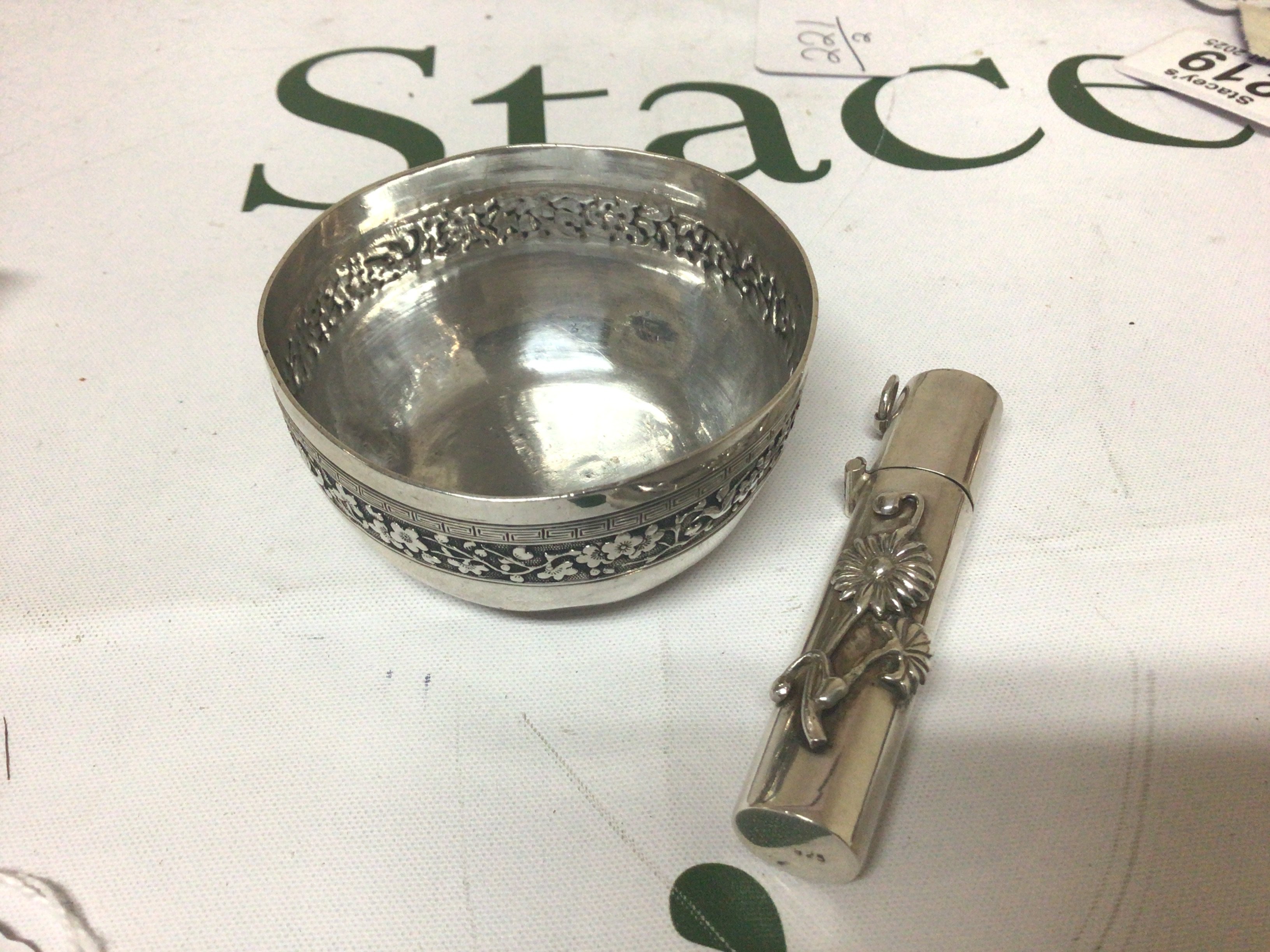 A Silver Chinese bowl with a floral pattern edge and Greek Key pattern marks to the base diameter 6.5cm and a round container with hinged top. (2)