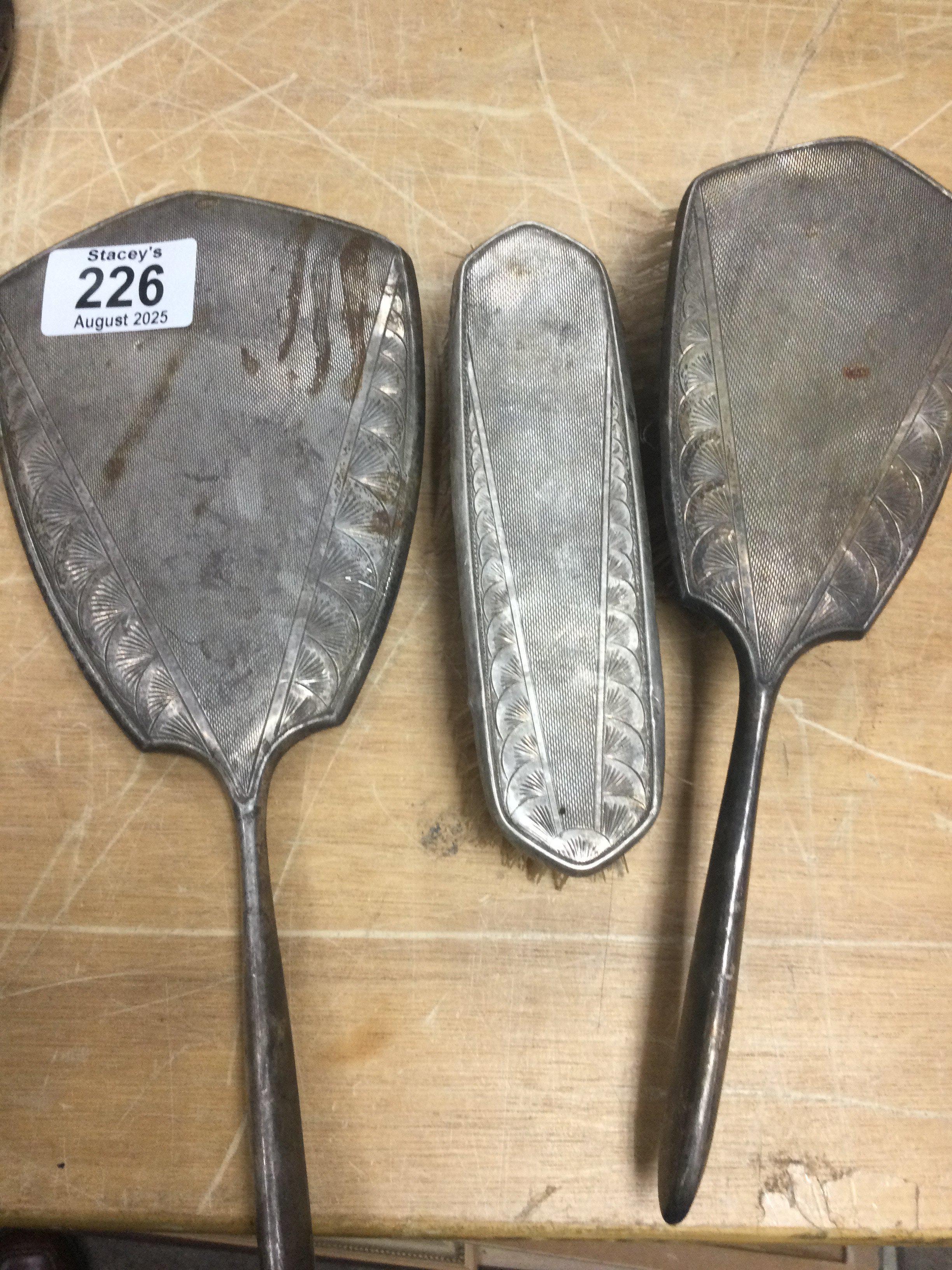 A three piece silver dressing set including a mirror and two brushes.