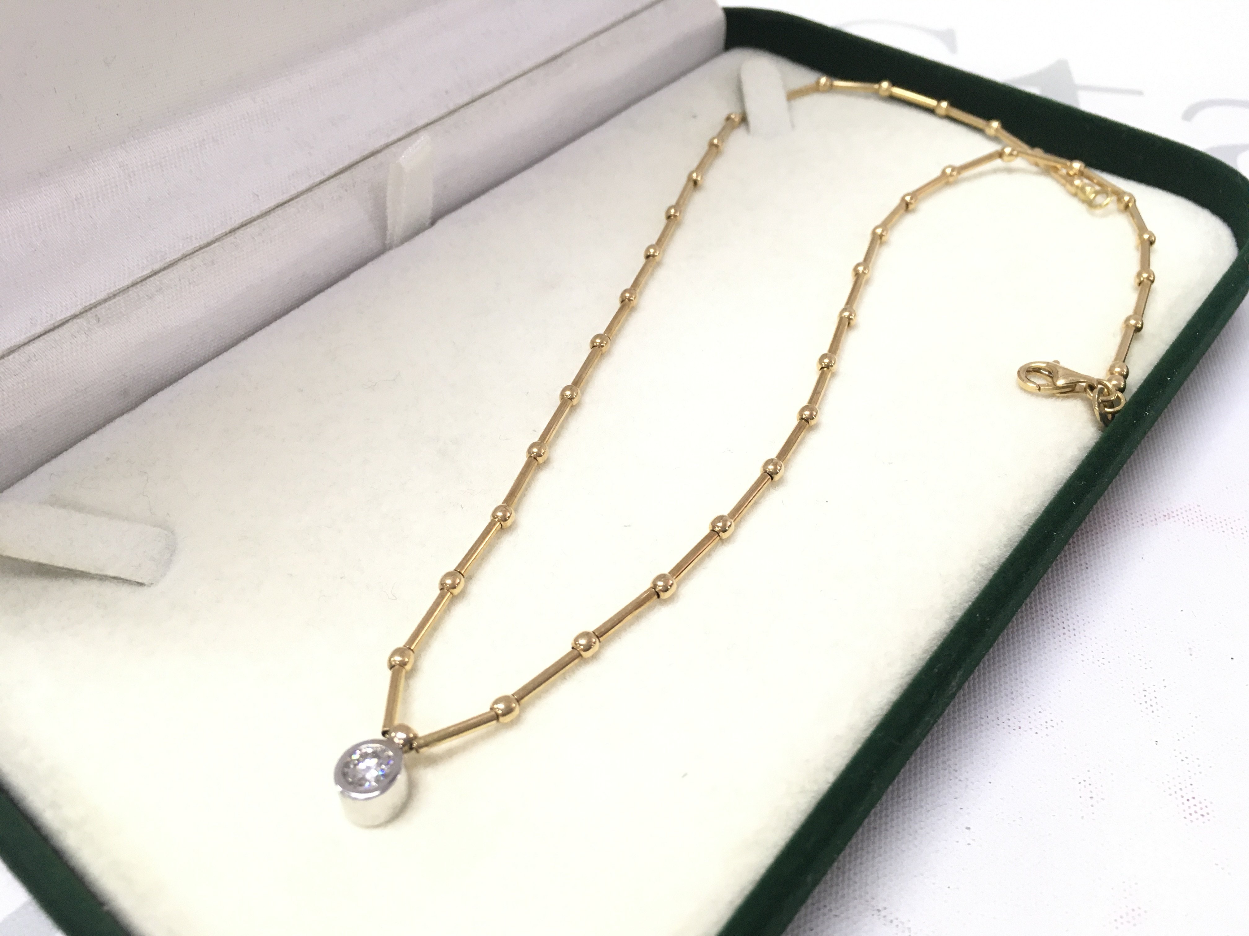 An 18ct necklace set with a rub over solitaire , 10g total weight approximately .postage category A