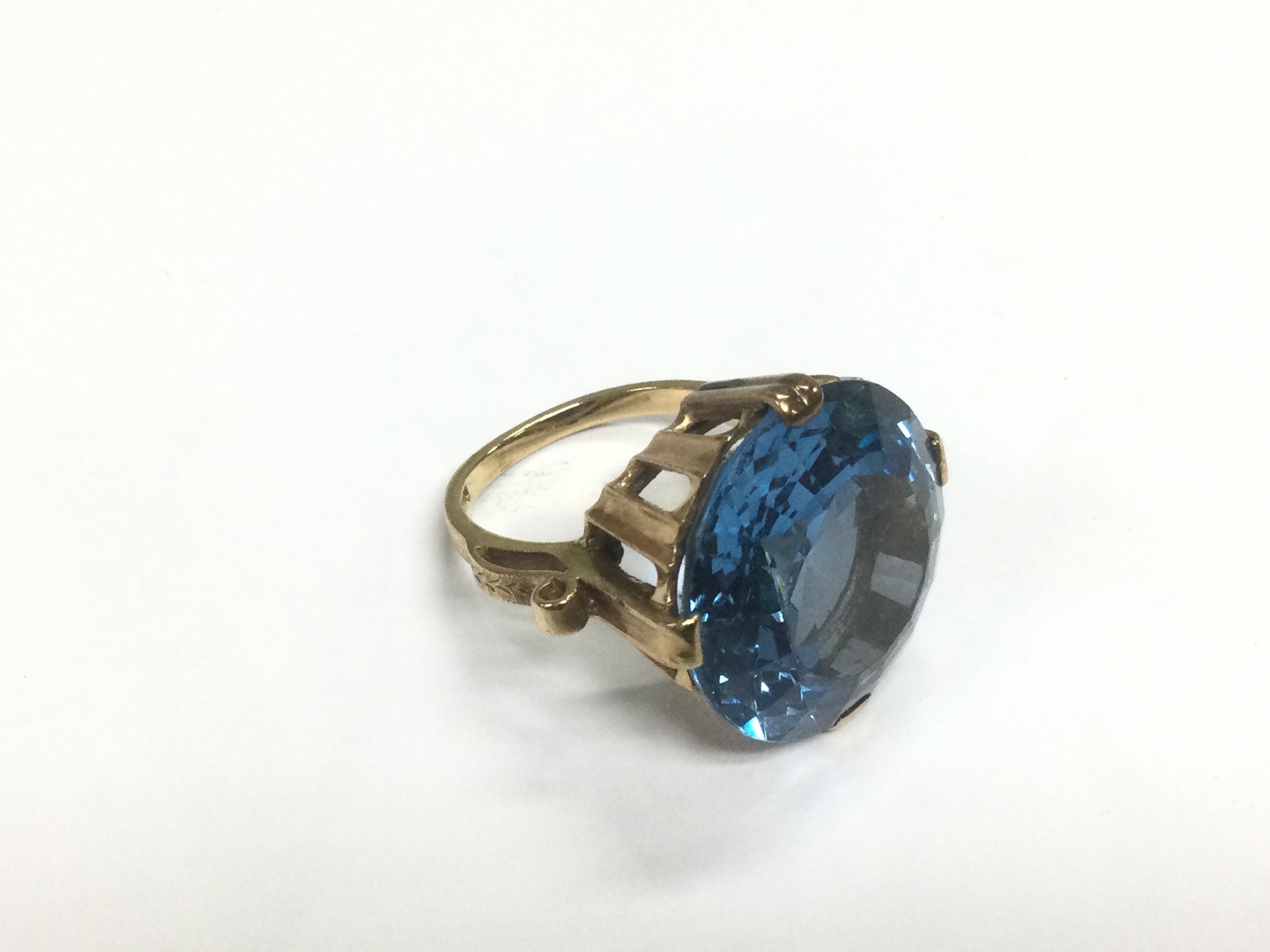 A gold ring set with a large blue stone, approx 113g and approx size N. Shipping category A.