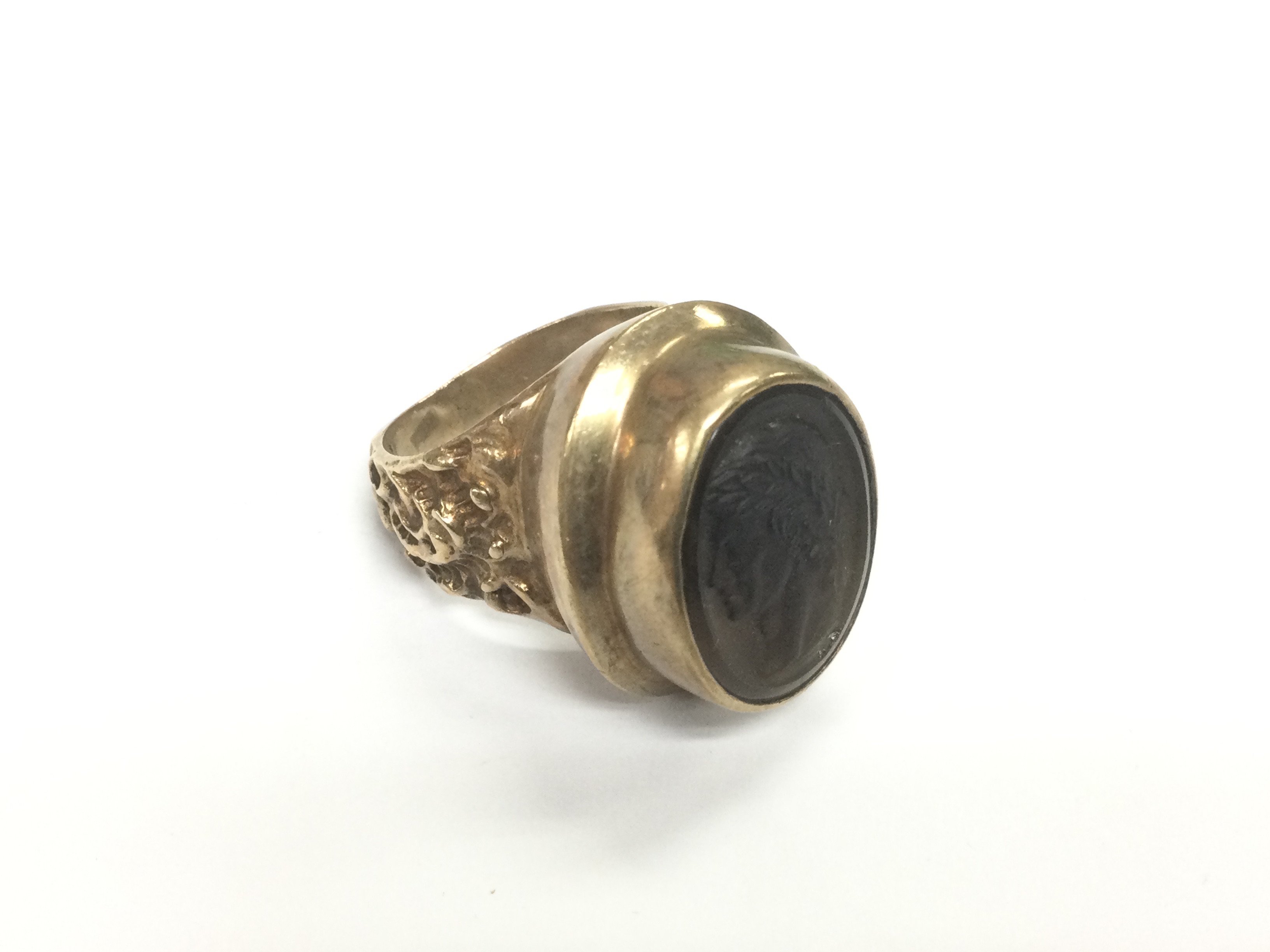 A 9ct gold ring set with an intaglio cut Romanesque figure in profile, approx 17.3g and approx size P. Shipping category A.