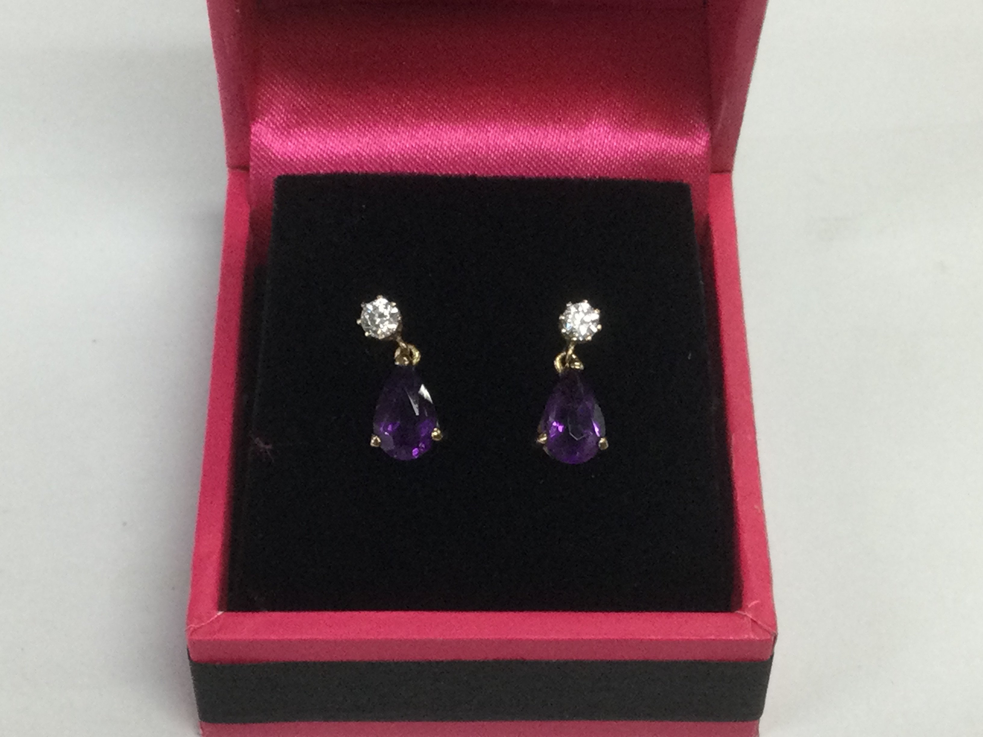 A pair of 9ct gold drop earrings set with a diamond and amethyst. Shipping category A.