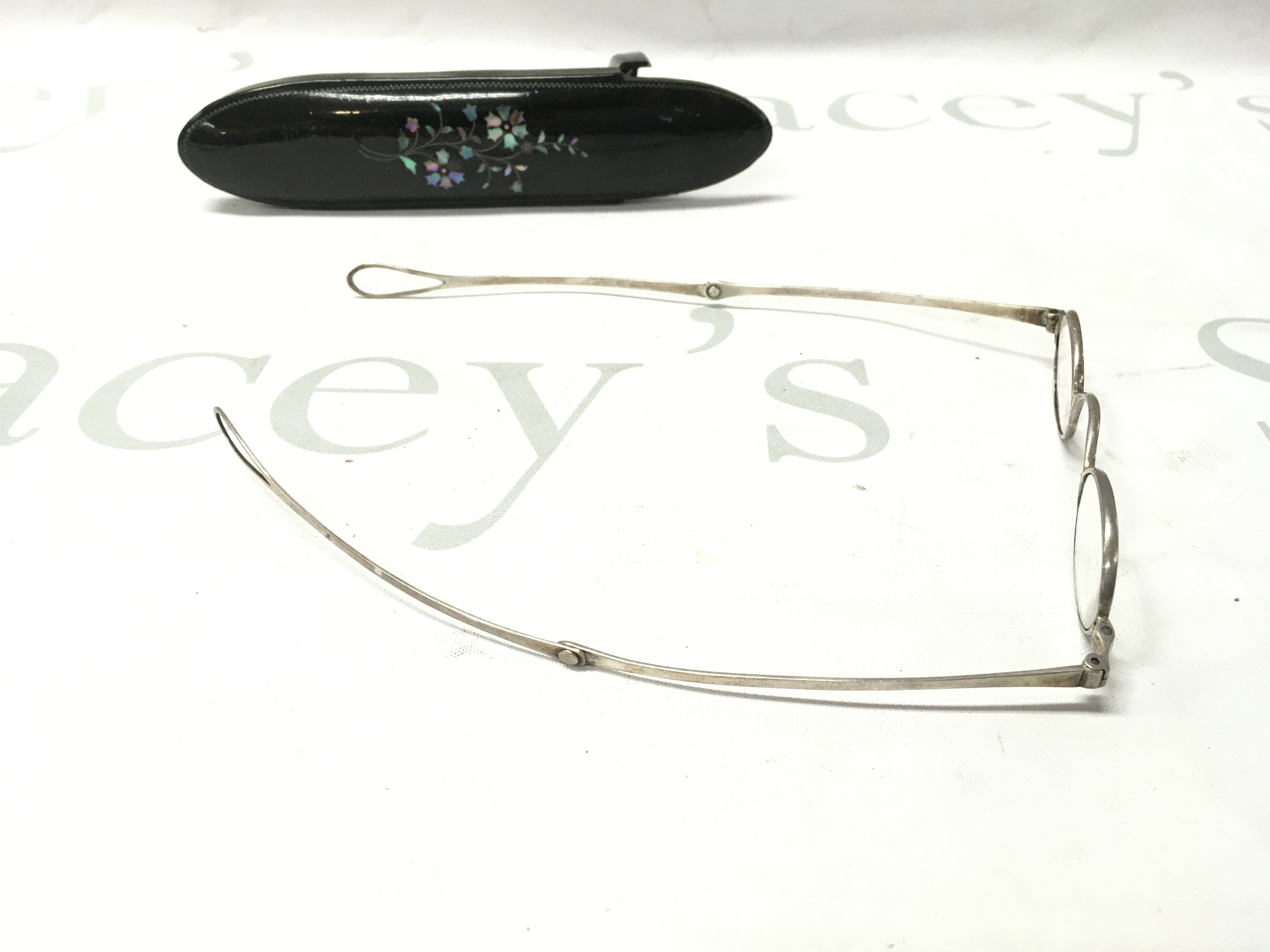 A pair of silver spectacles in a case.