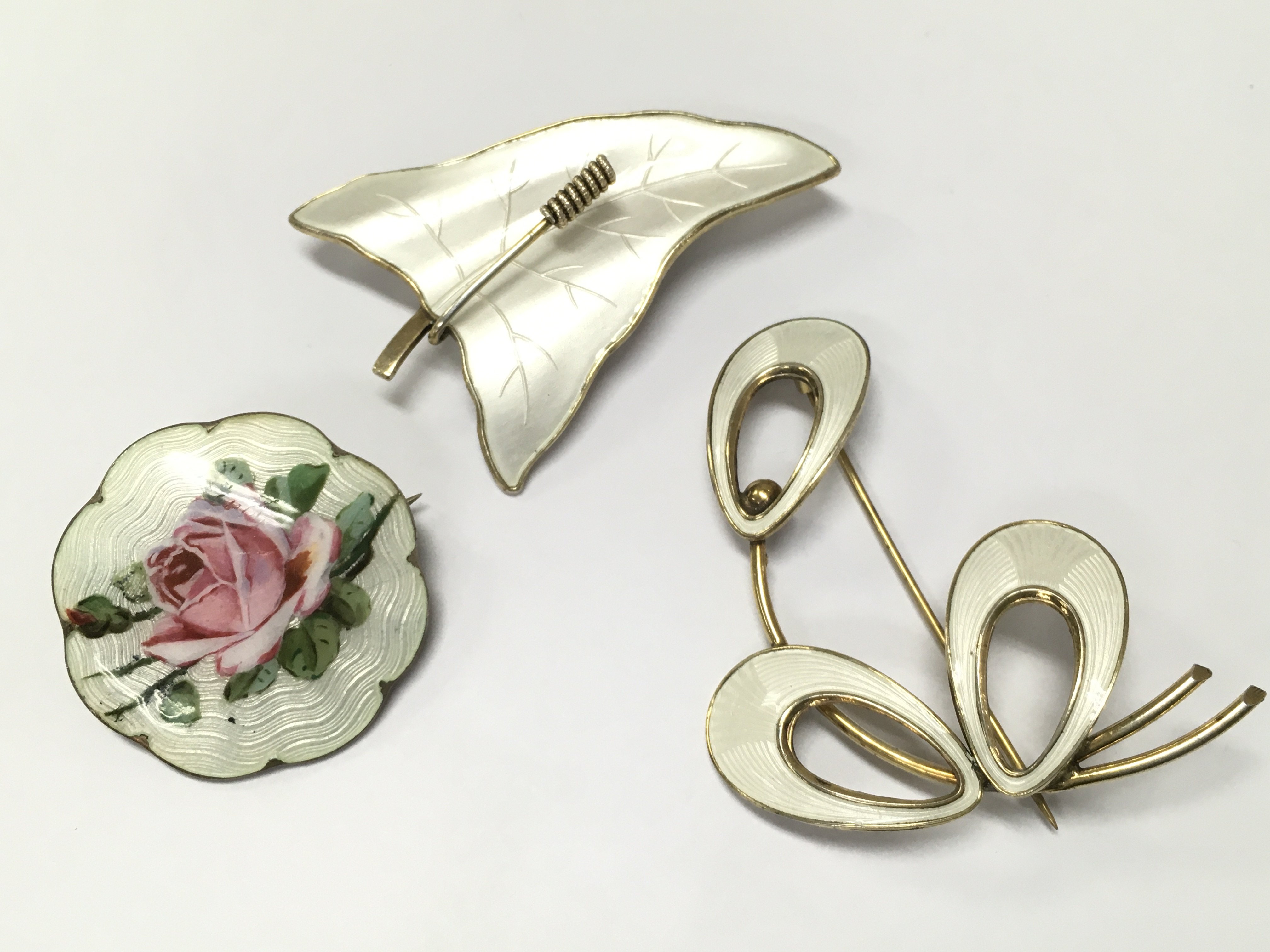 Three enamel brooches including a Norwegian sterling silver brooch and other silver brooches . Postage category A