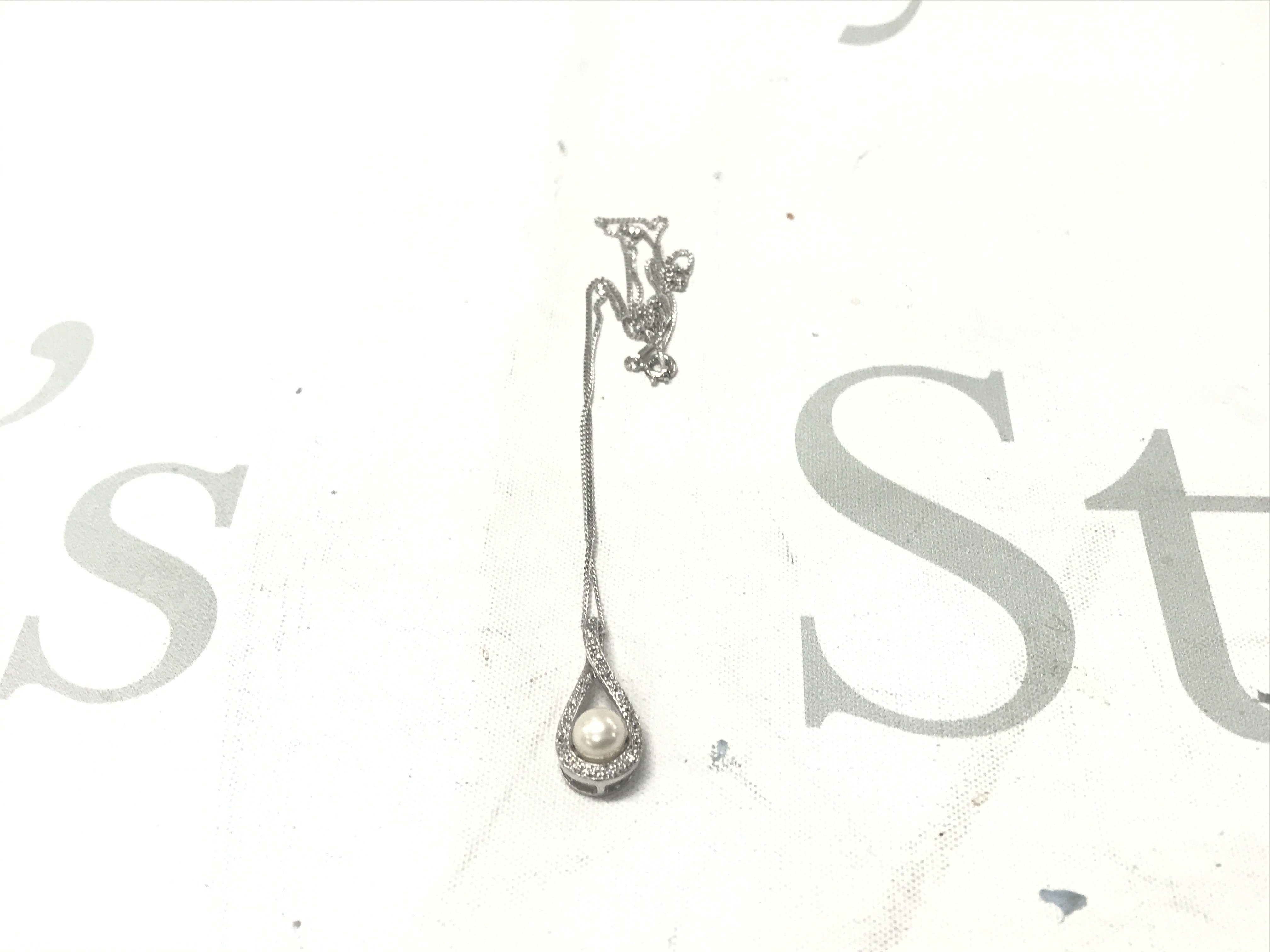 Silver pear-shaped pendant set with a cultured pearl and white cubic zirconia, on a silver chain.