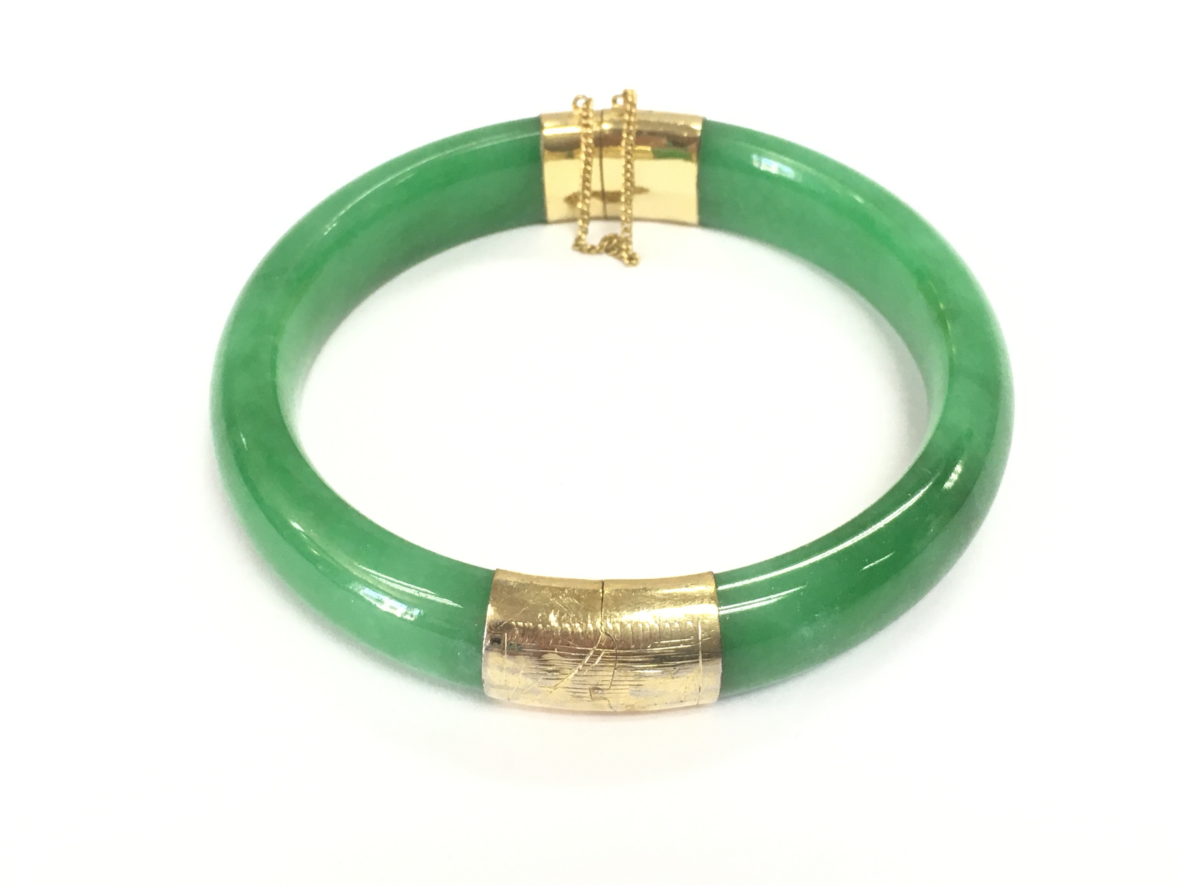 A jade bangle with 14ct gold. Approx 7cm diameter.Postage B