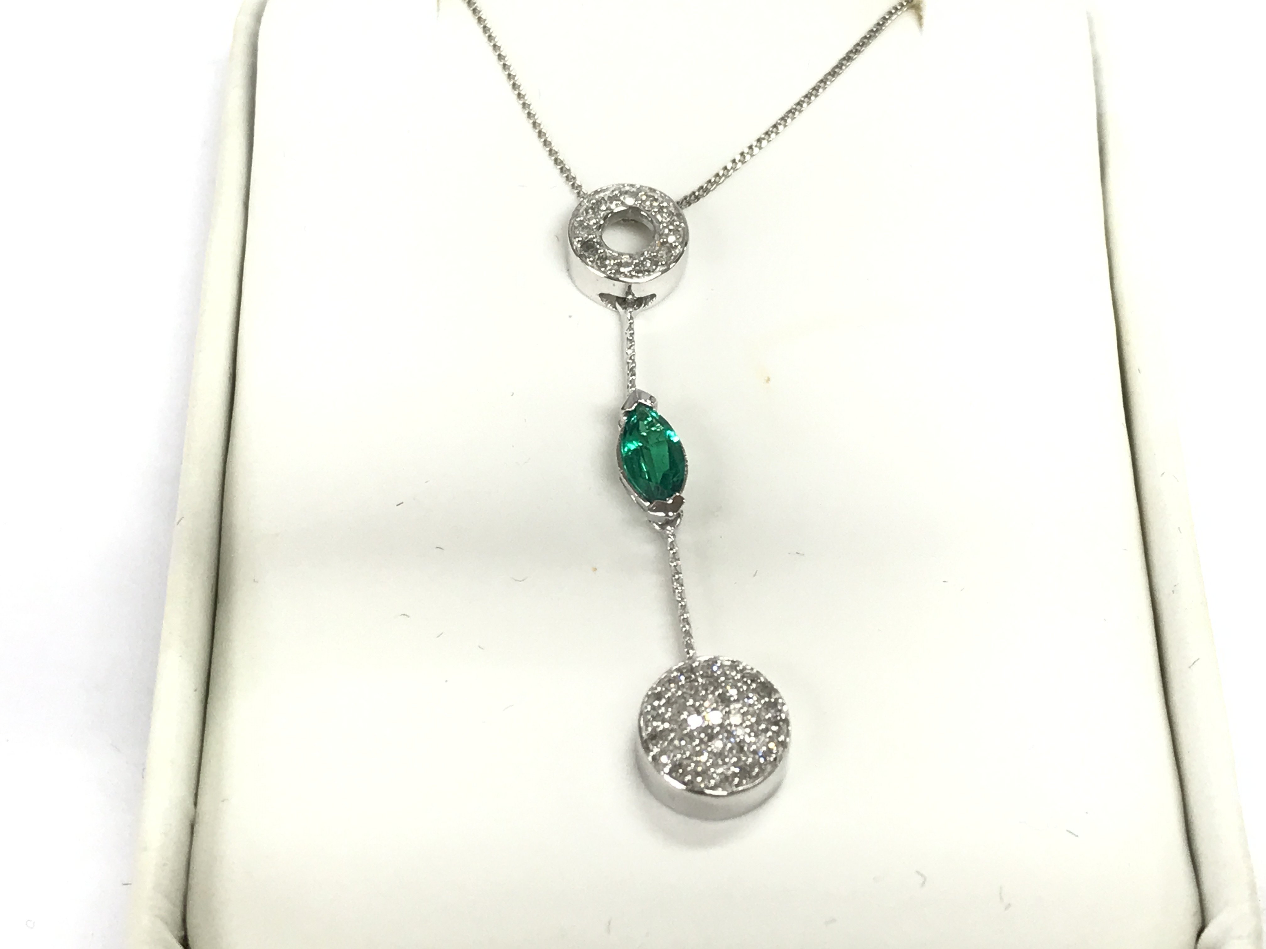 A 9ct gold necklace set with small diamonds and an emerald. 2.46g