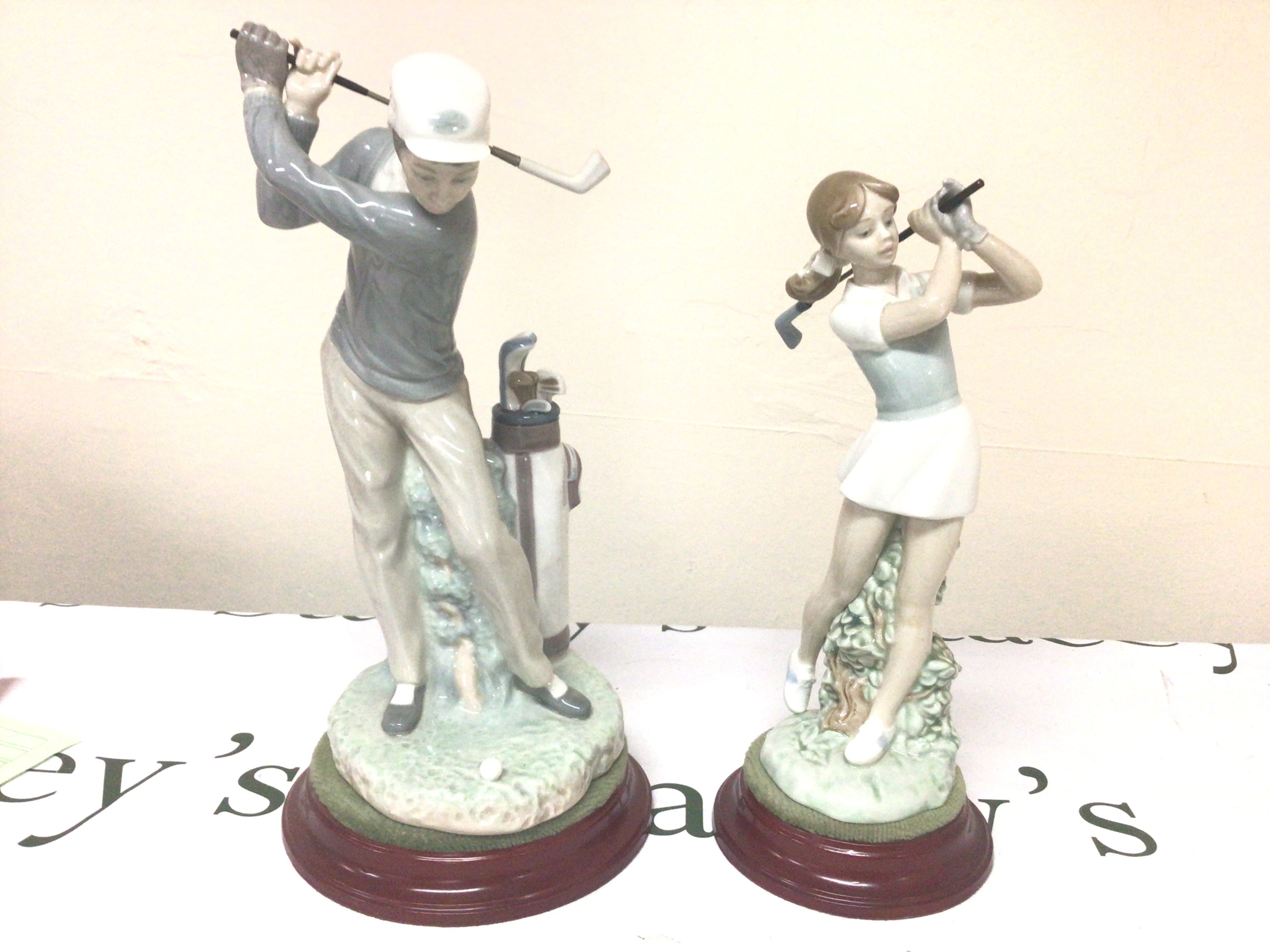 A Lladro figure of a Male Golfer in action and a conforming NAO female figure no obvious damage (2)