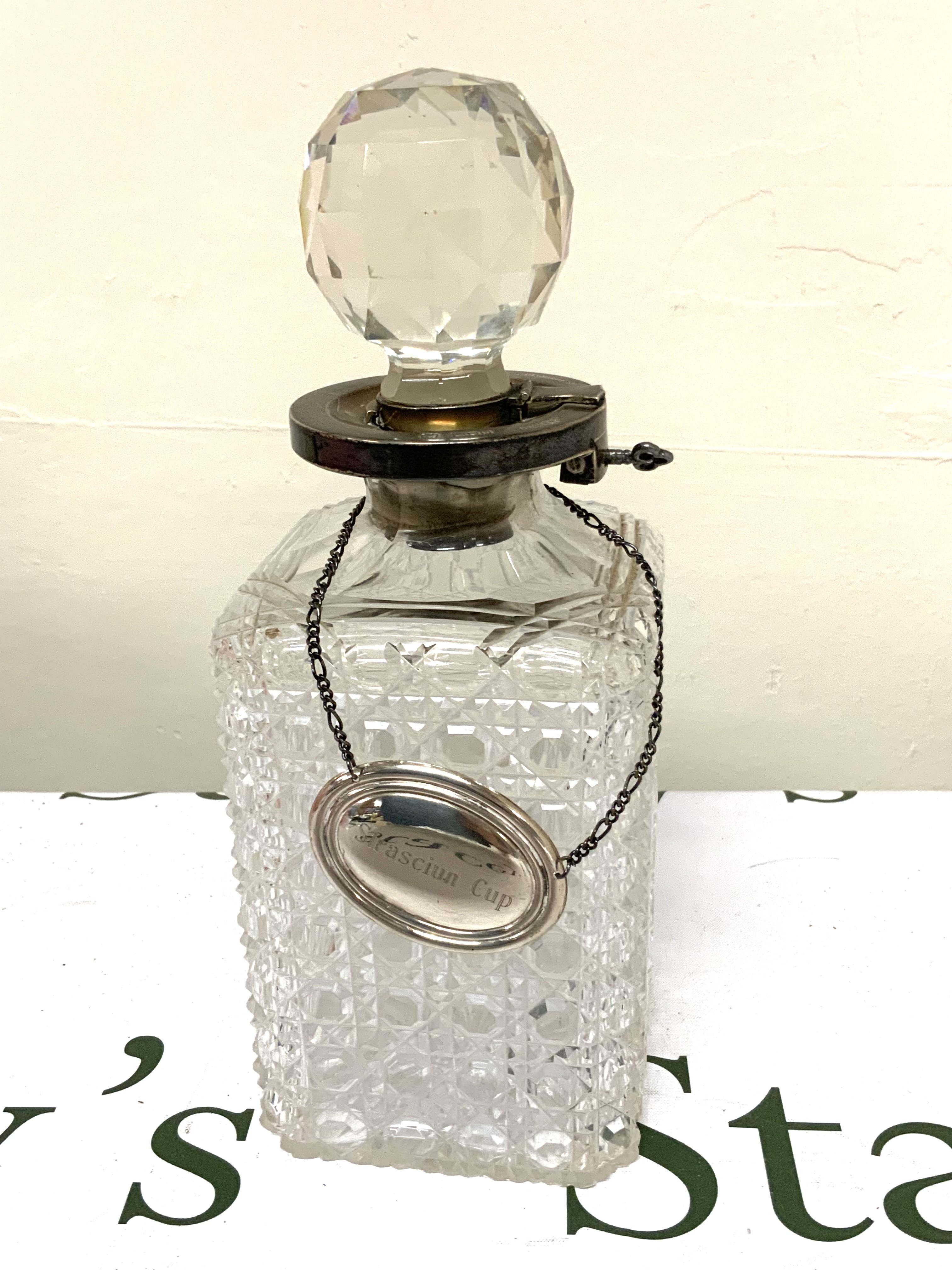 A cut crystal whisky decanter with hallmarked silver mounts, label and Silver locking top. 25cm.