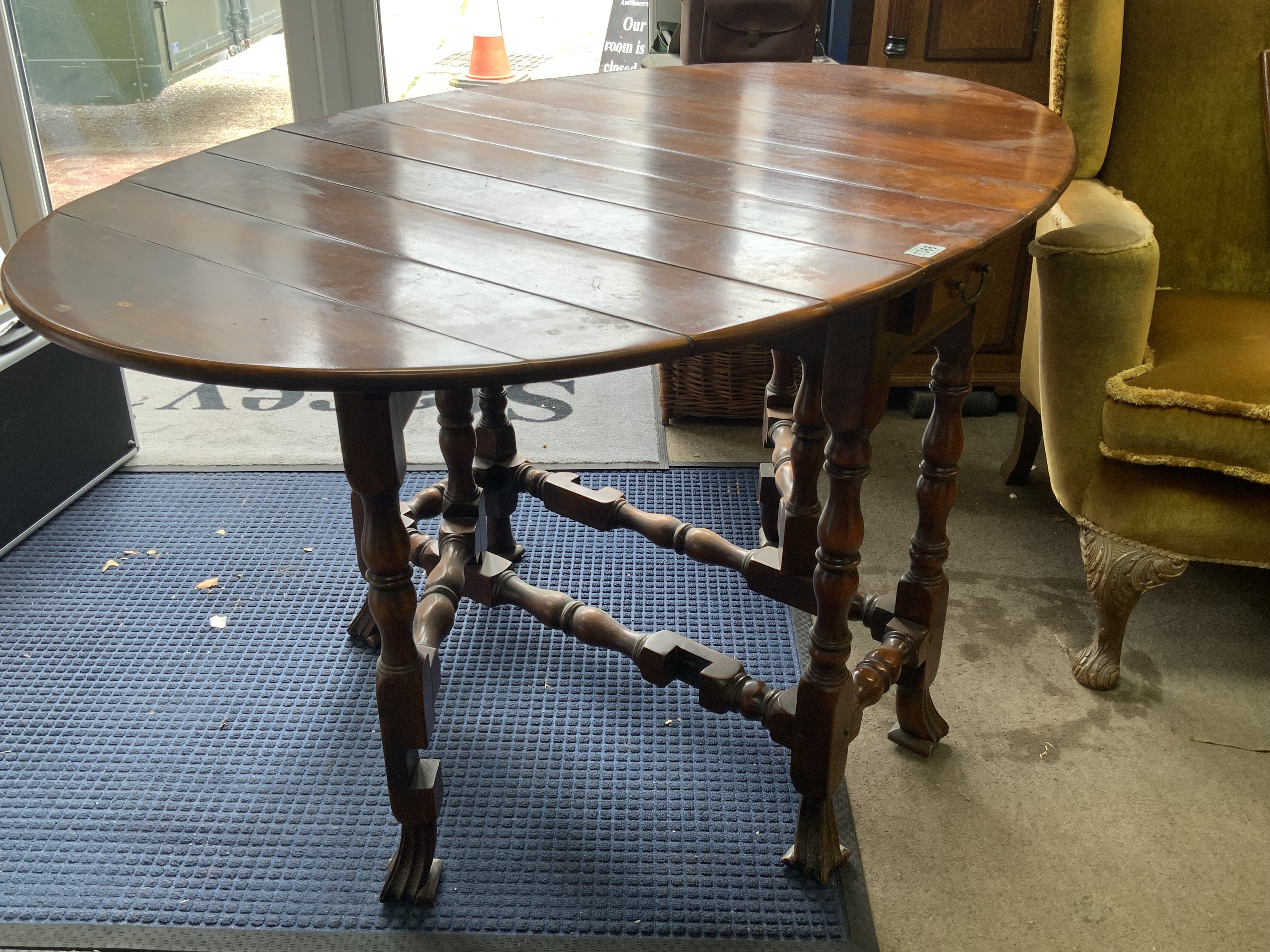 A carved hardwood oval drop leaf dining table with plank top. 143cm x 91cm x 77cm