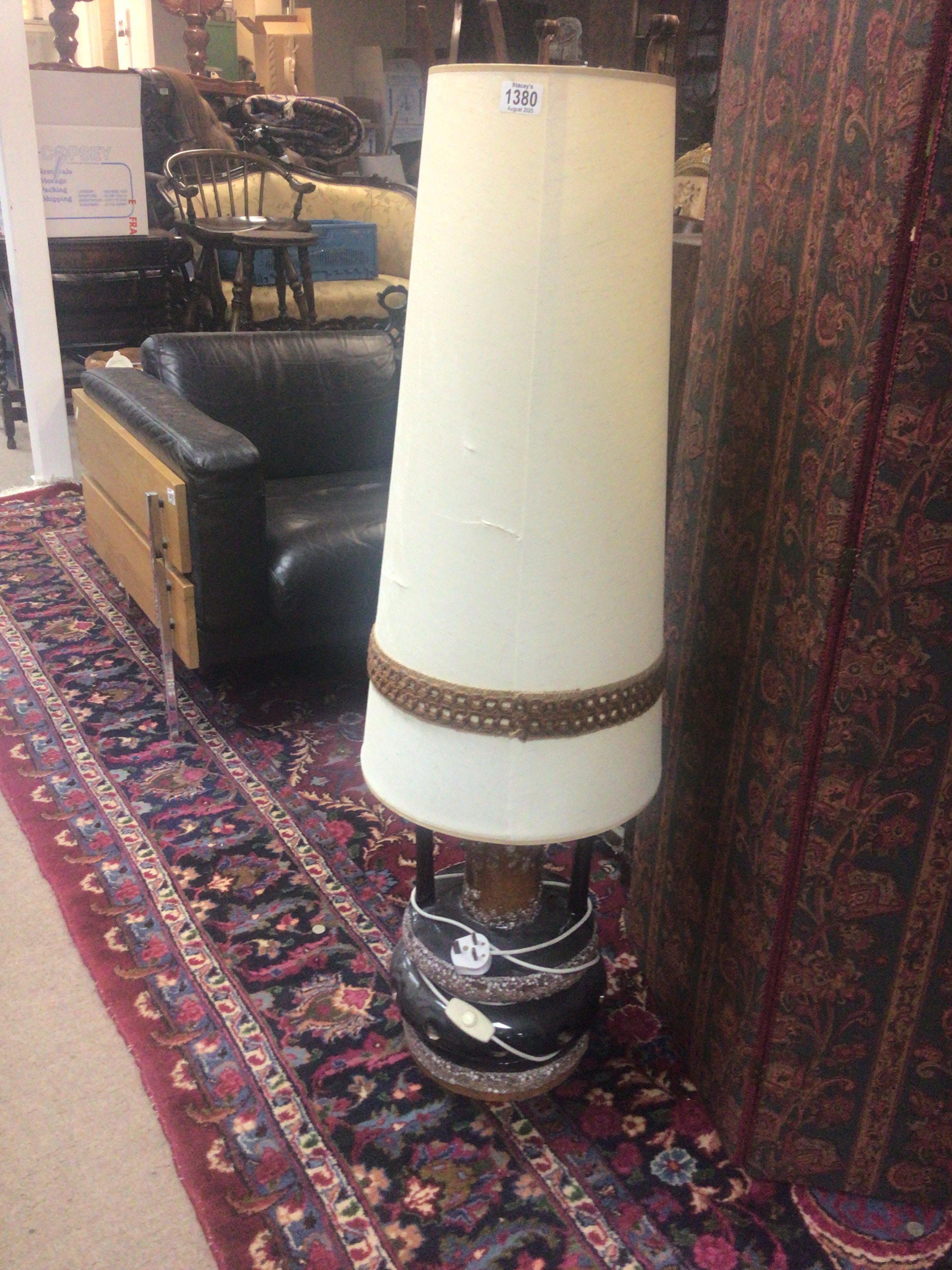 A mid 20th century floor lamp with a brown glazed ceramic base and elongated shade.
