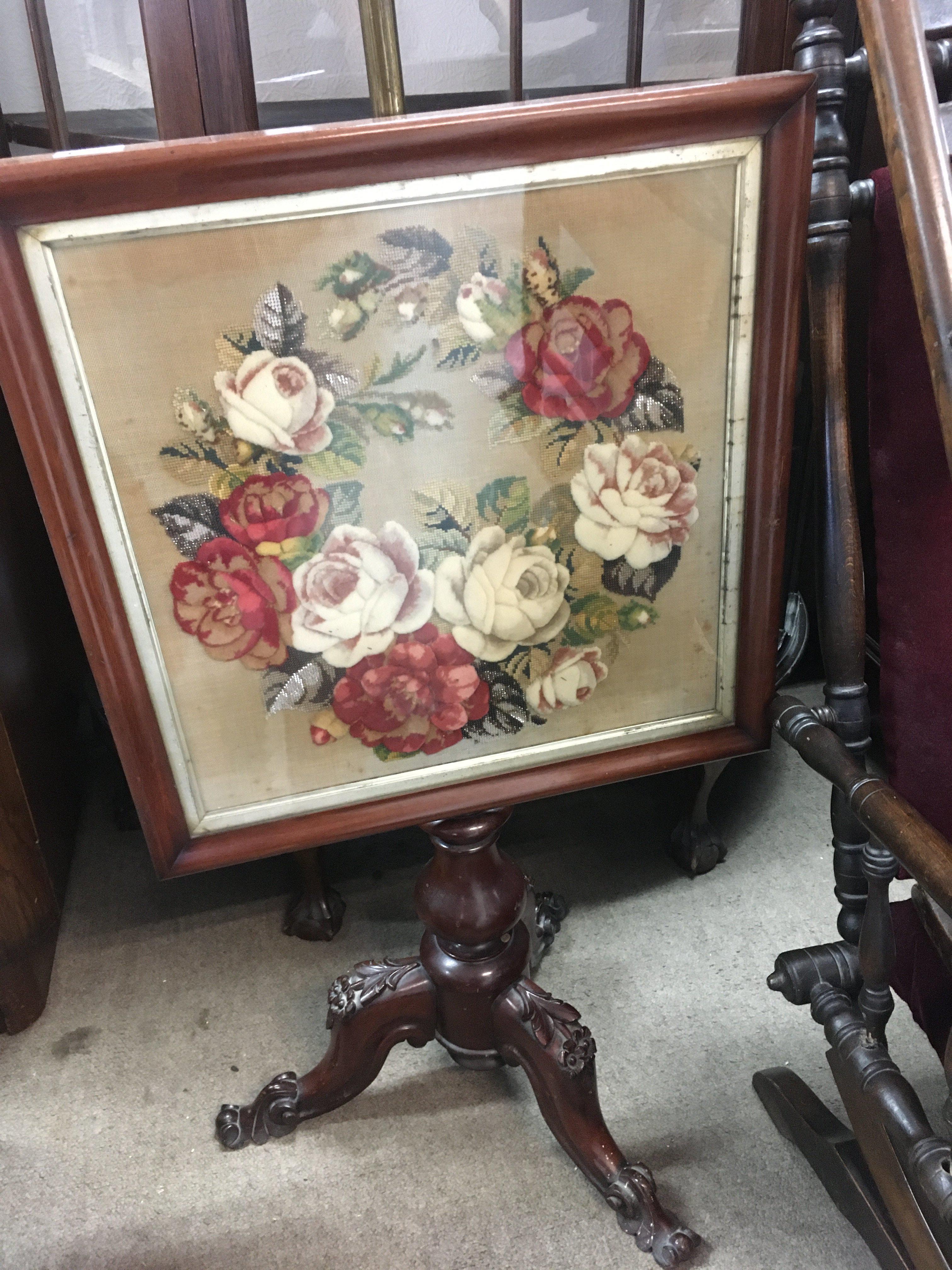A Victorian mahogany fire screen the rectangle frame inset with a floral tapestry.