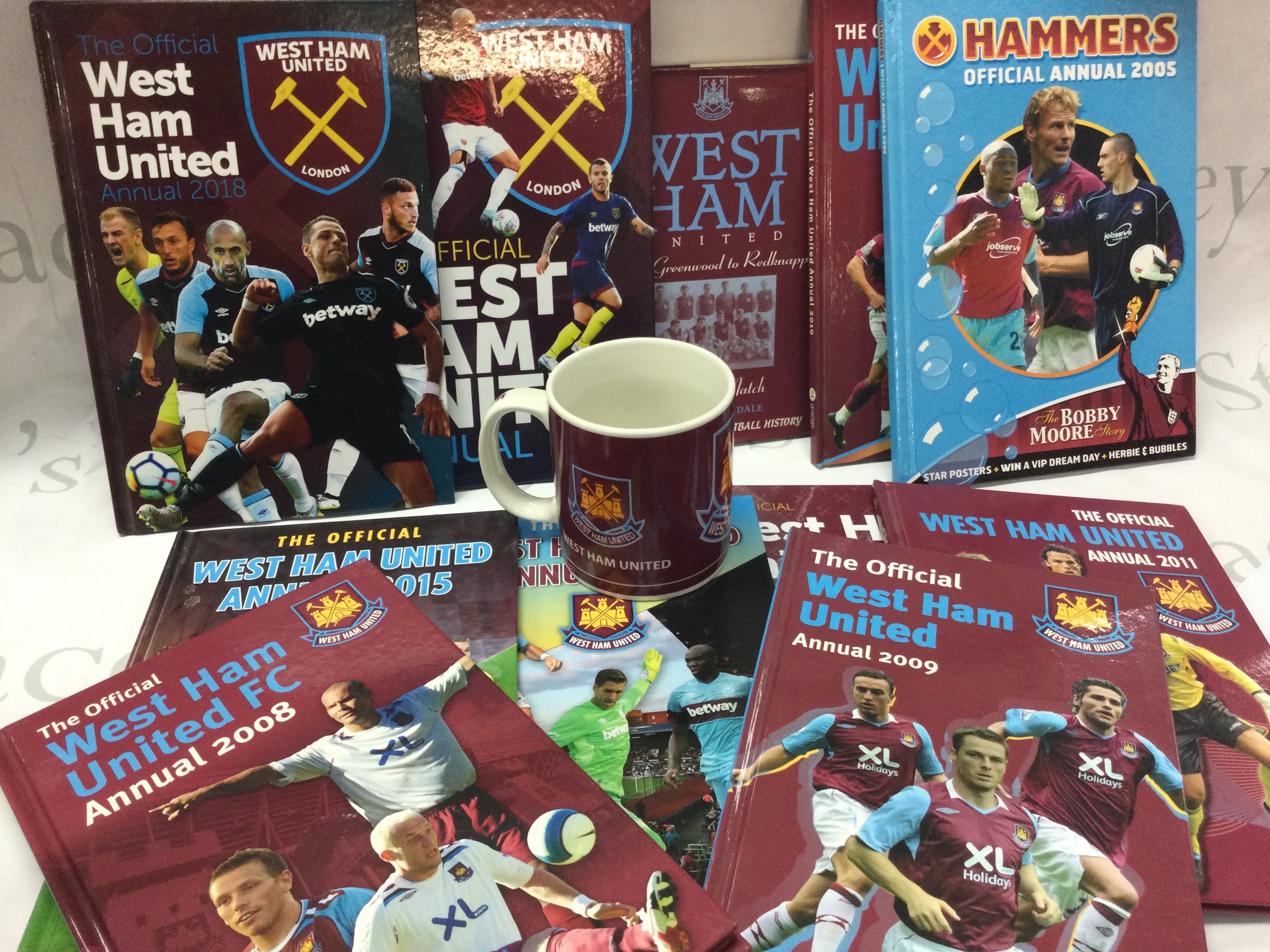 A collection of West Ham United items including official annuals from 2005 to 2019 a statistics book and a large mug . No reserve This lot cannot be posted