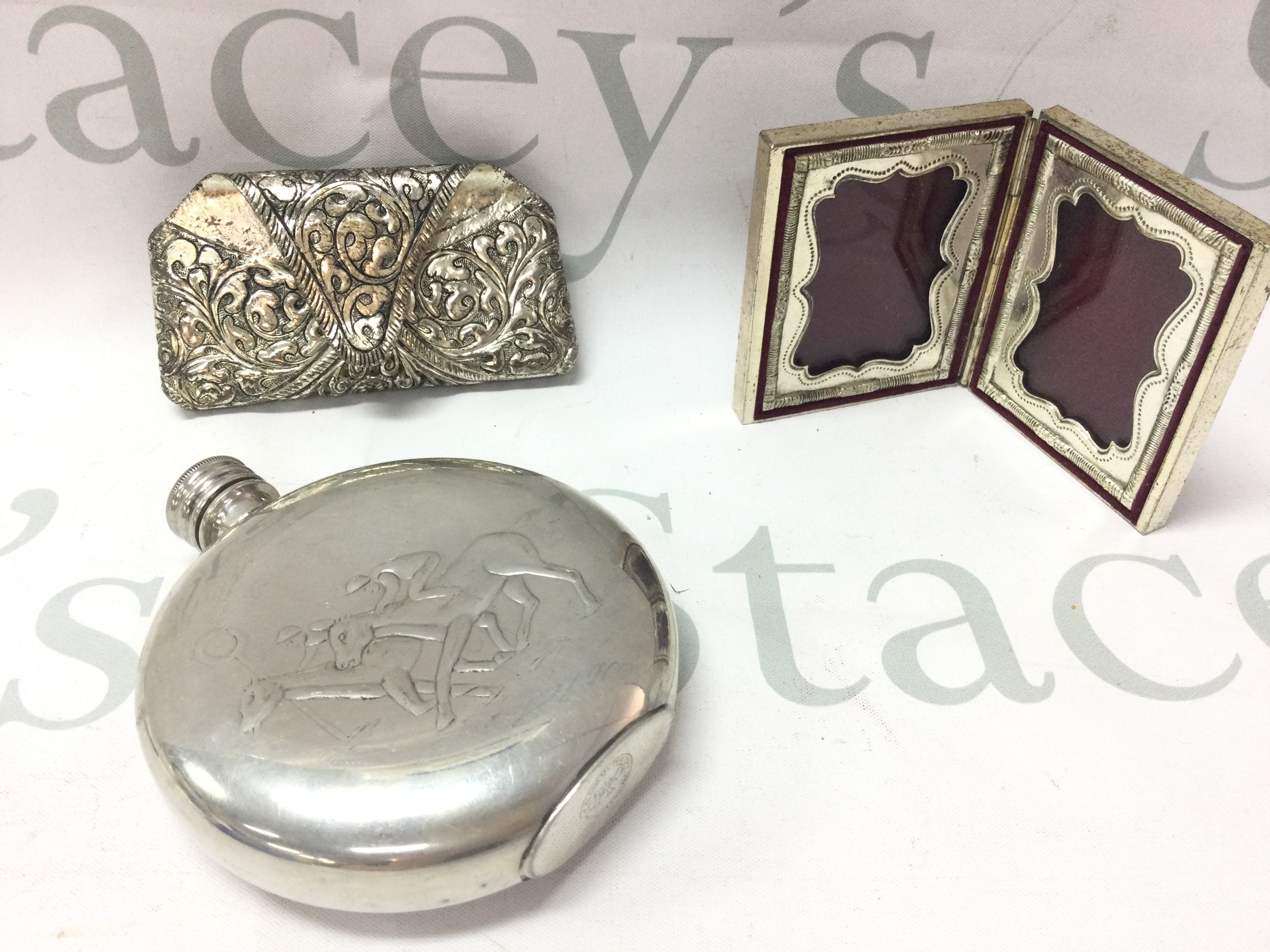 A small silver plate round hip flask decorated with two racehorses and a small heavy double photo frame embossed and a silver plated hanging item. Postage category B