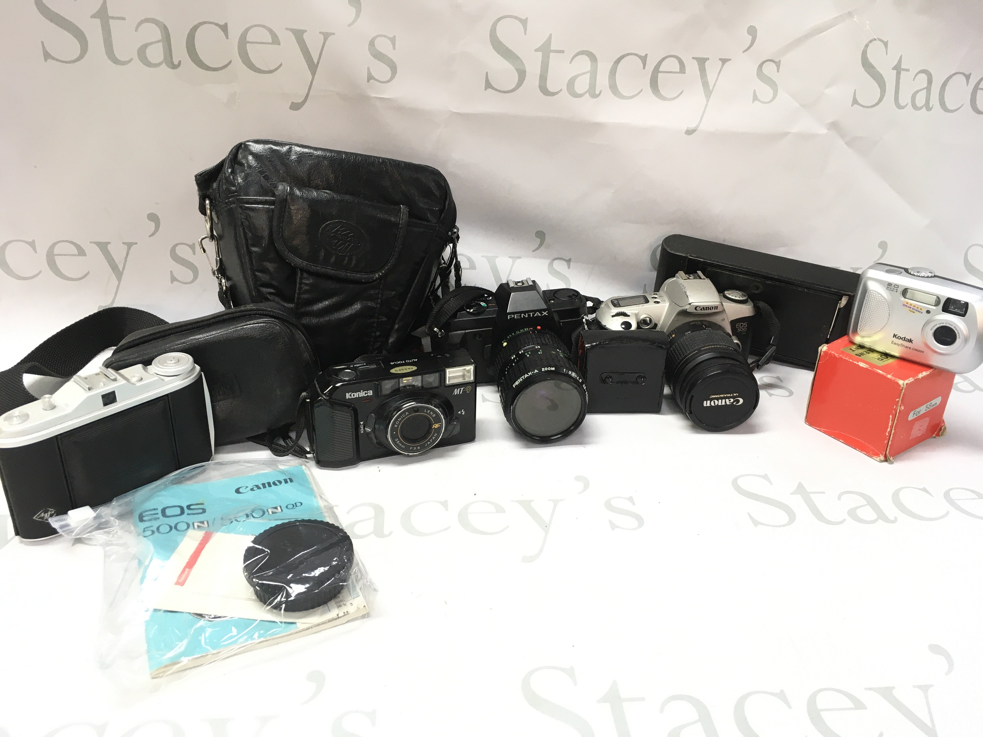 A box of vintage cameras including Agfa Isolette I, Konica MT-9, Pentax P30N, Canon EOS 500N, Kodak Easyshare CX6200