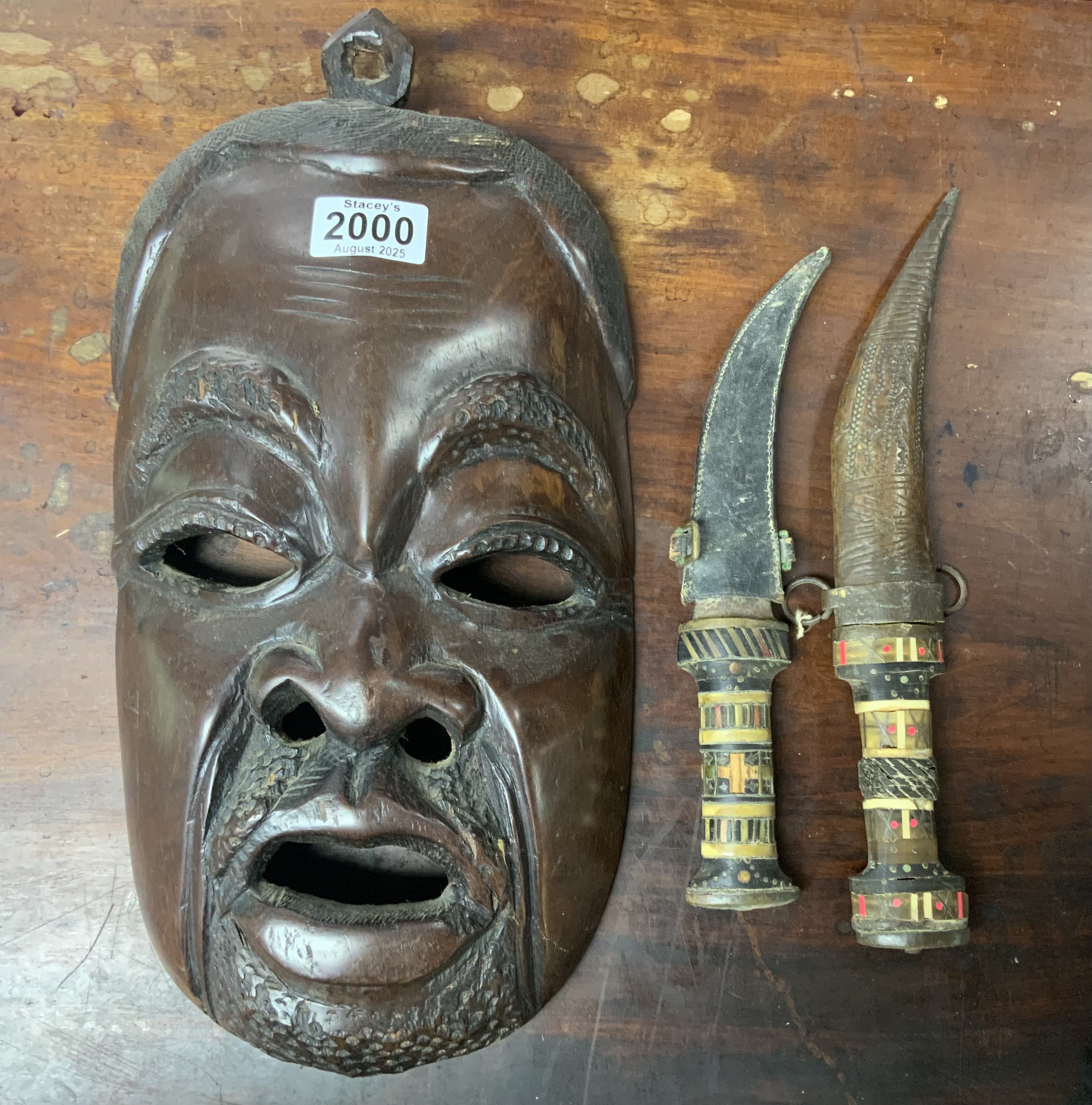 A carved hardwood tribal mask together what to bone inlaid sheathed knives.
