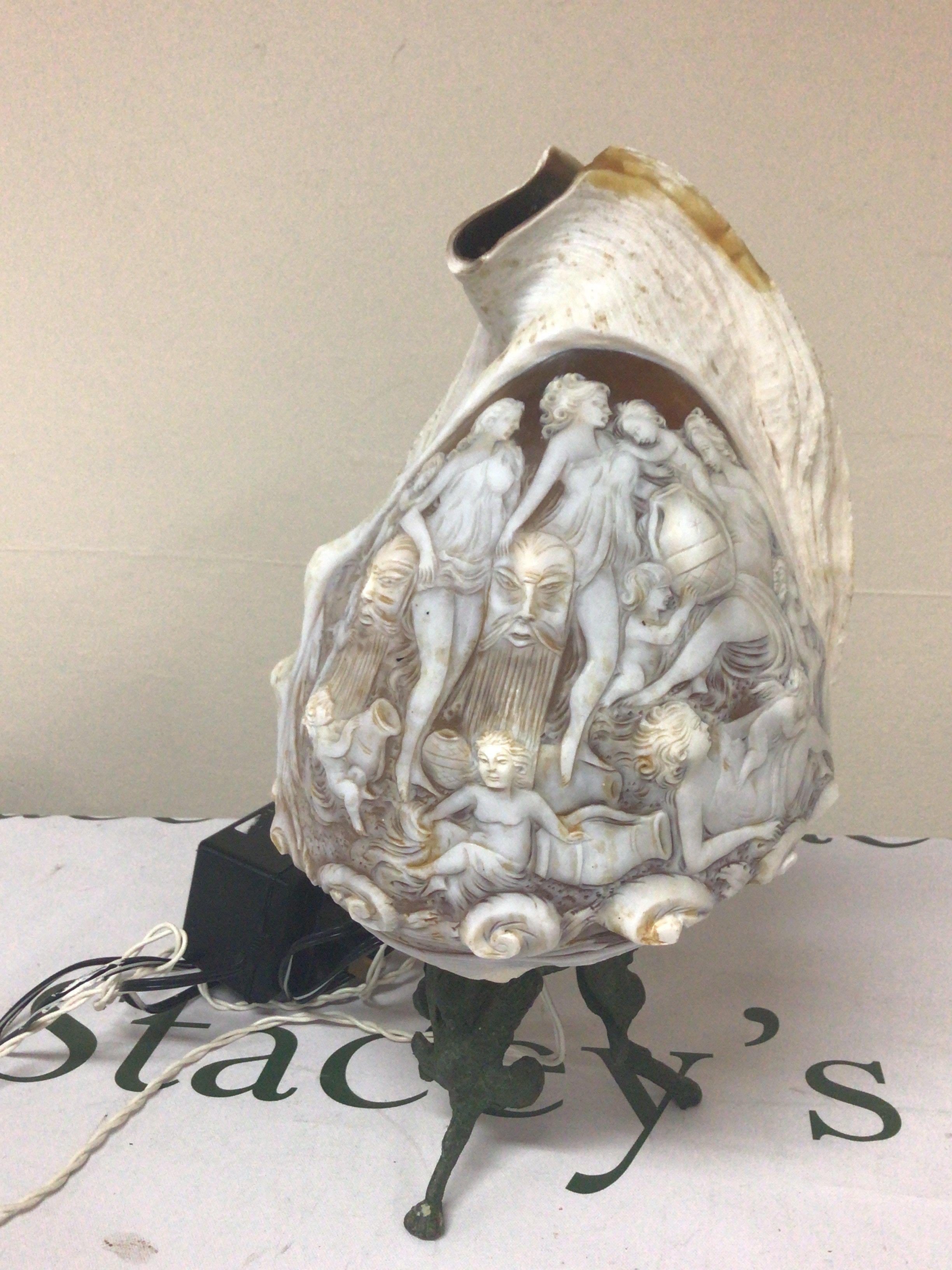 A quality Carved Cameo Conch shells on a metal stand. The shell carved with neo-classical female figure with raised masks. Total hight including stand 28cm. later fitted for electric.