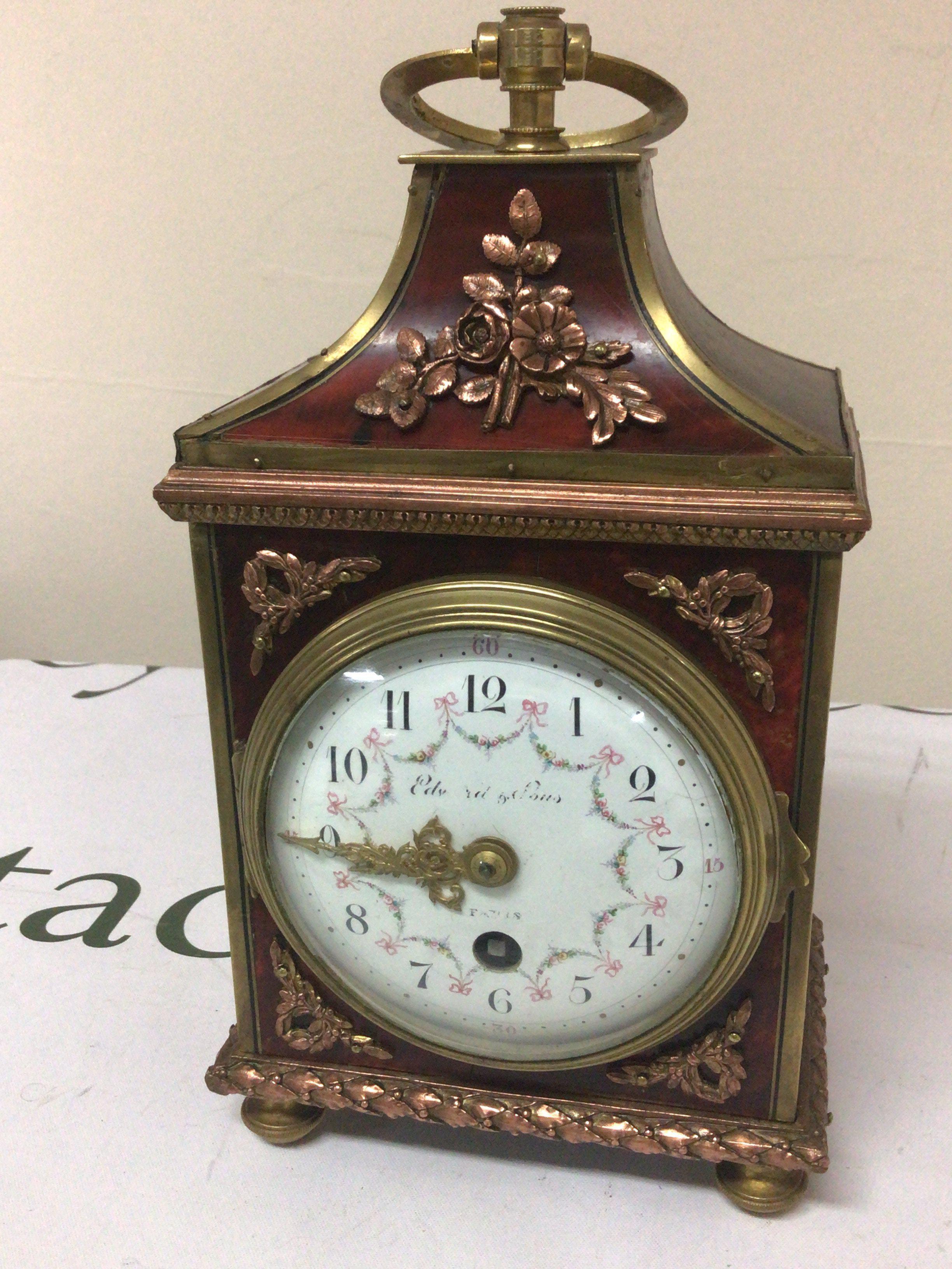 A French Clock with applied copper and brass floral ornamentation. The painted dial with garlands brass movement with key. Height 29cm