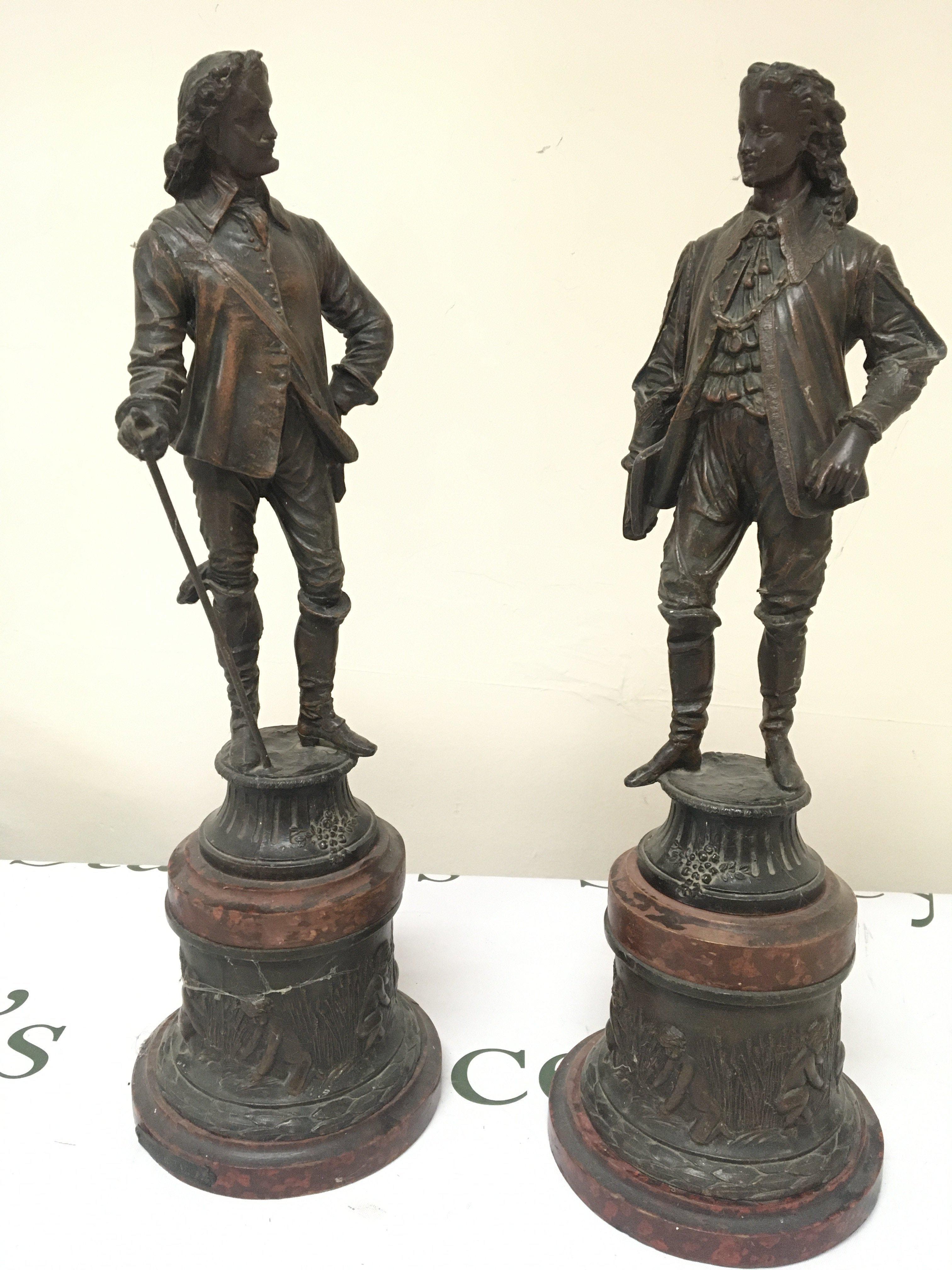 A pair of Spelter figures in 17th century style dress on simulated marble bases (2)