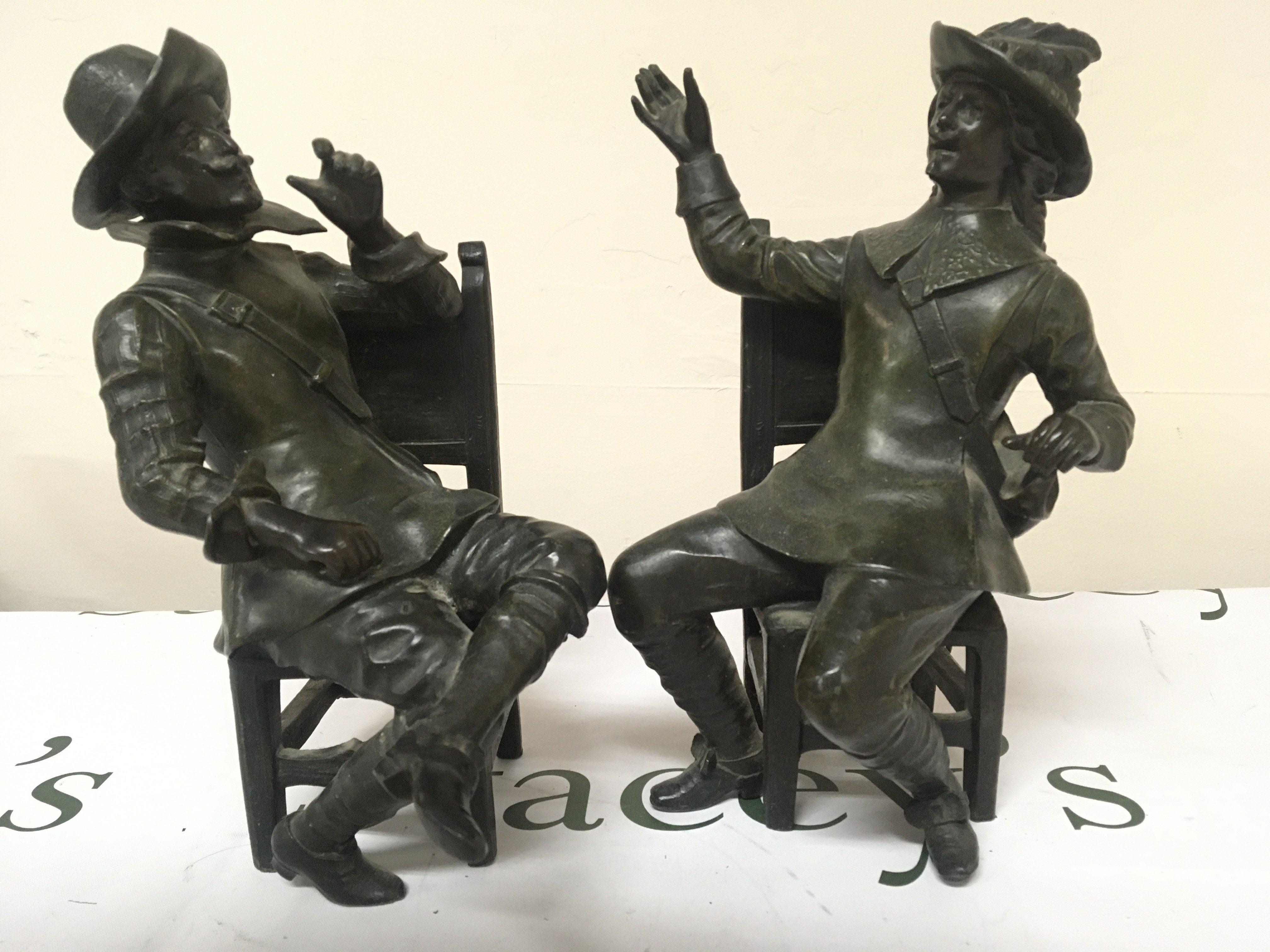 A pair of bronzed metal figures of seated cavaliers the chair rail stamped Geo Maxim (2) Height 26cm one leg damaged.