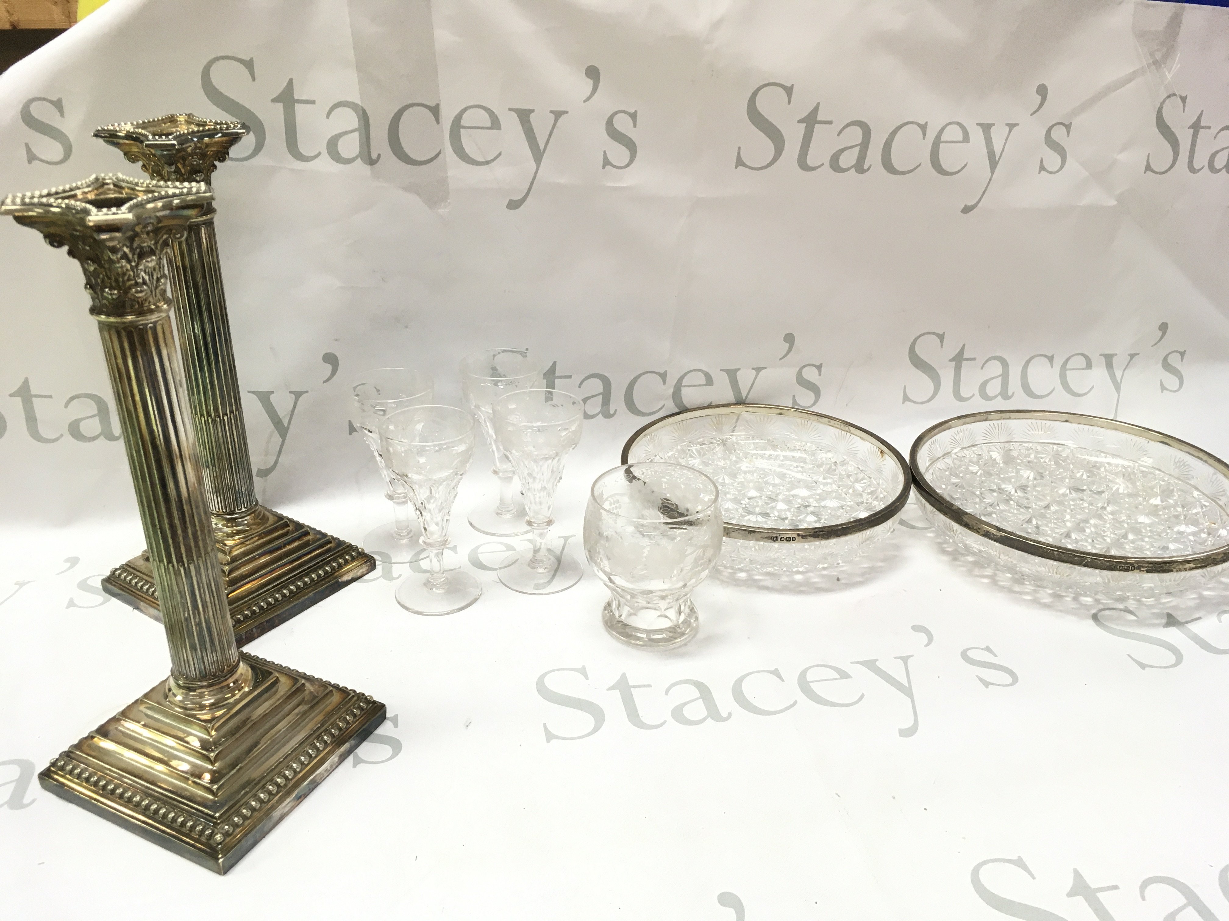 Crystal cut glass bowls with silver hallmarked rims, fruiting vine glasses , a pair of silver plated Corinthian candlesticks (29cm tall) This lot cannot be posted
