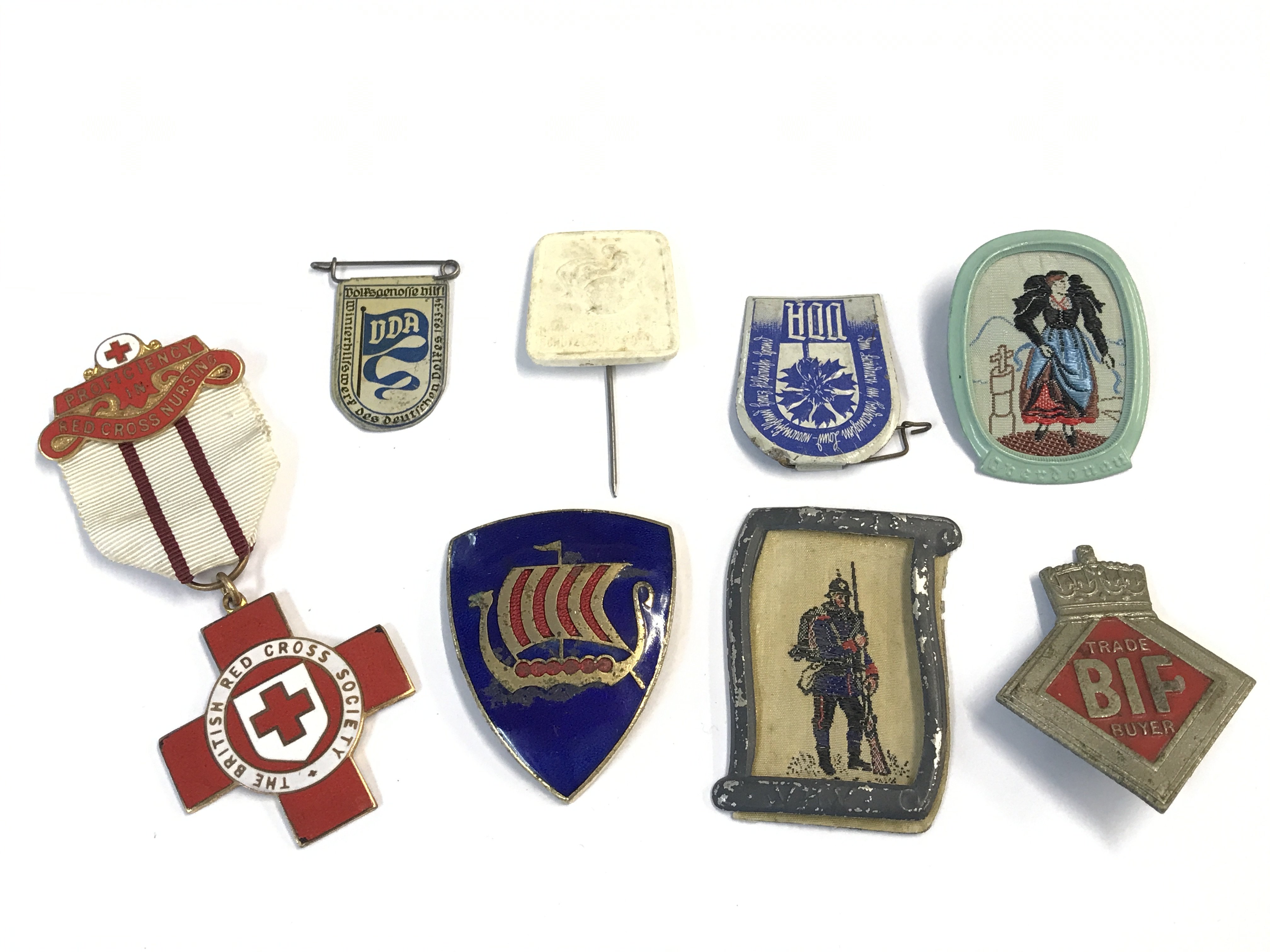 A collection of Badges including a British BIF trade buyers badge numbered back A32276 rare badge, a British Red Cross medal awrded to 39390 NH Rouse and other mid 20th century badges. Postage category A