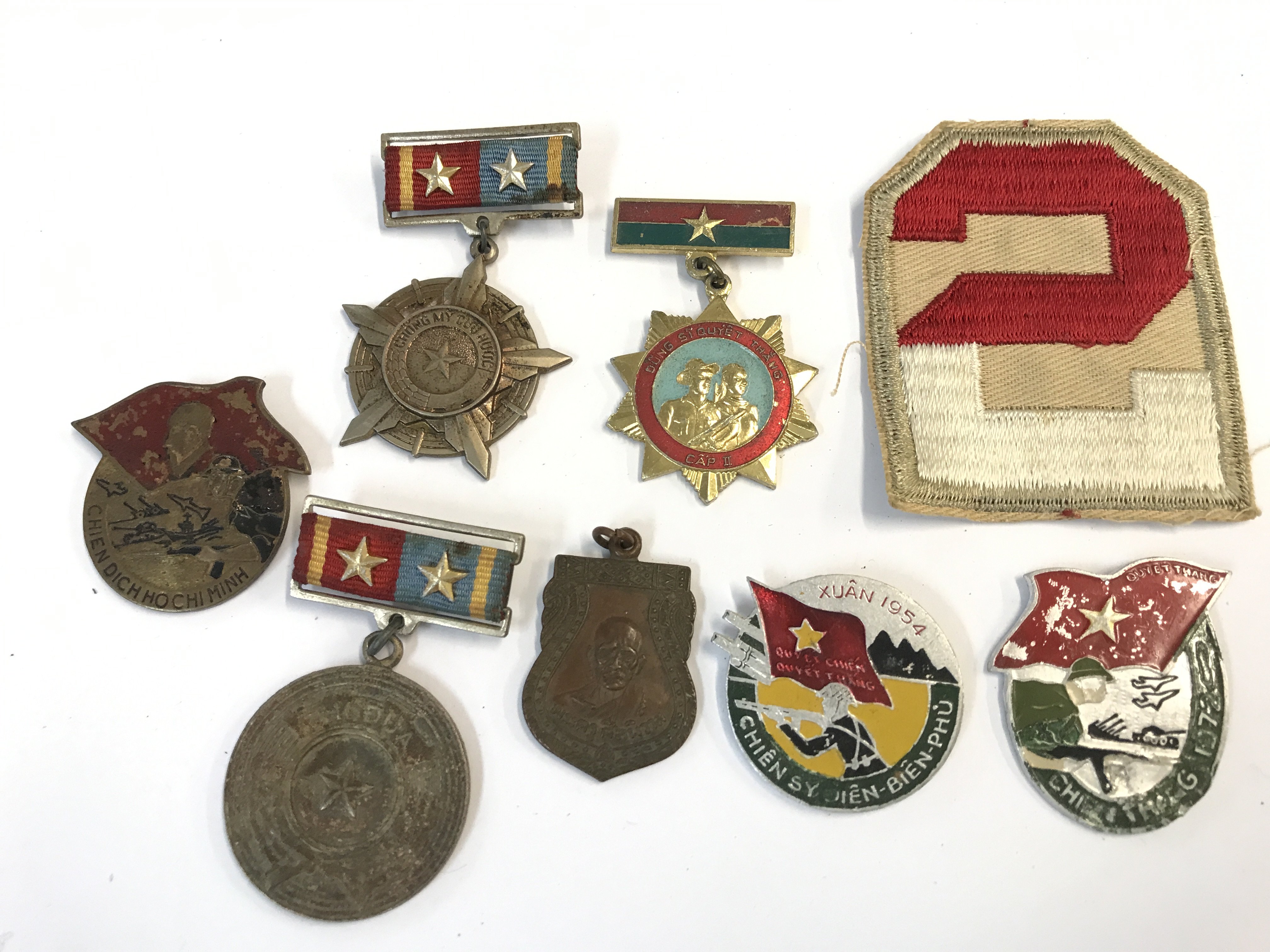 A collection of Vietnam war badges and medals and an American military South Pacific badge.