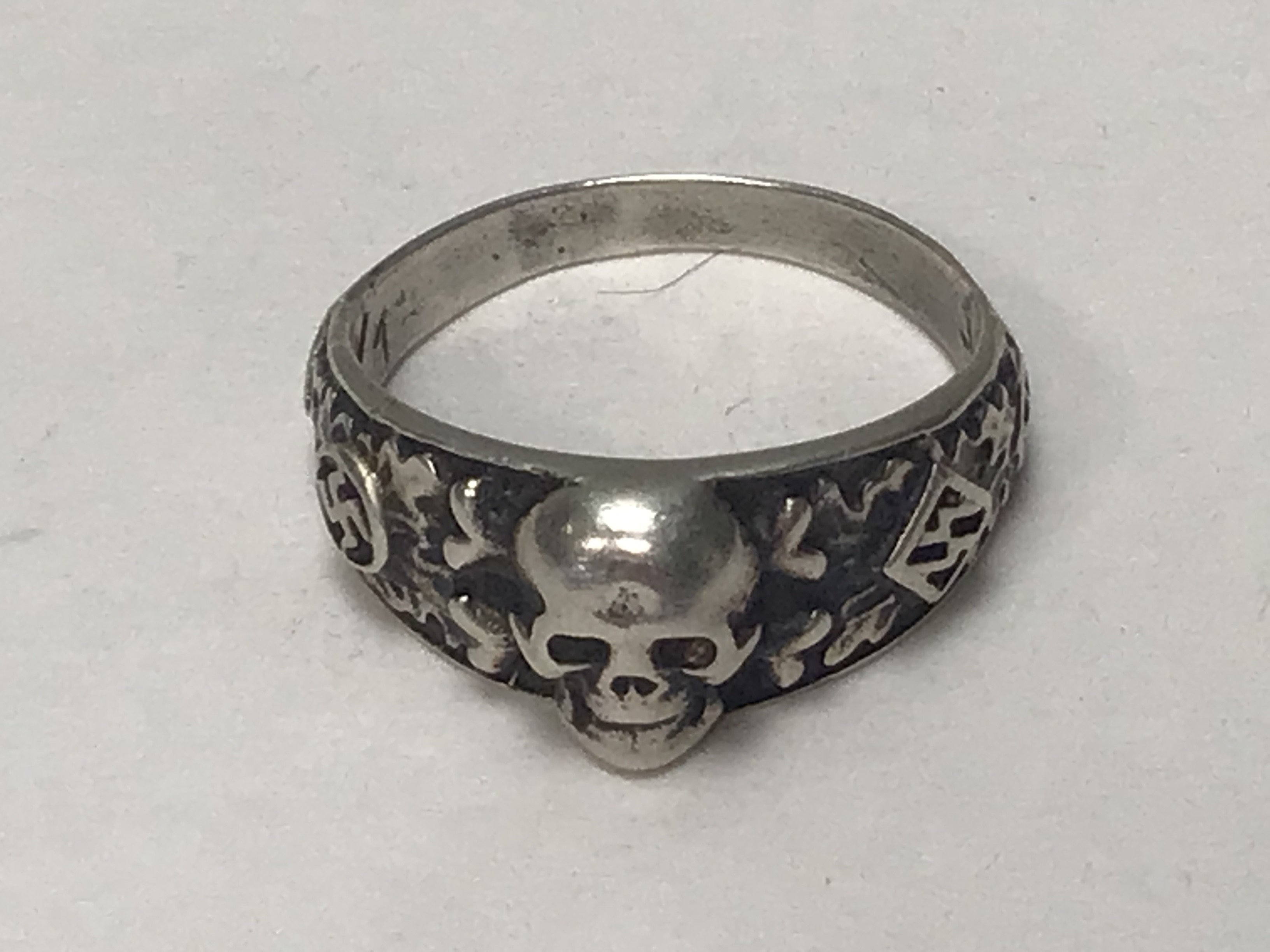 A German Third Reich SS white metal ring with raised skull the inner band with inscription.