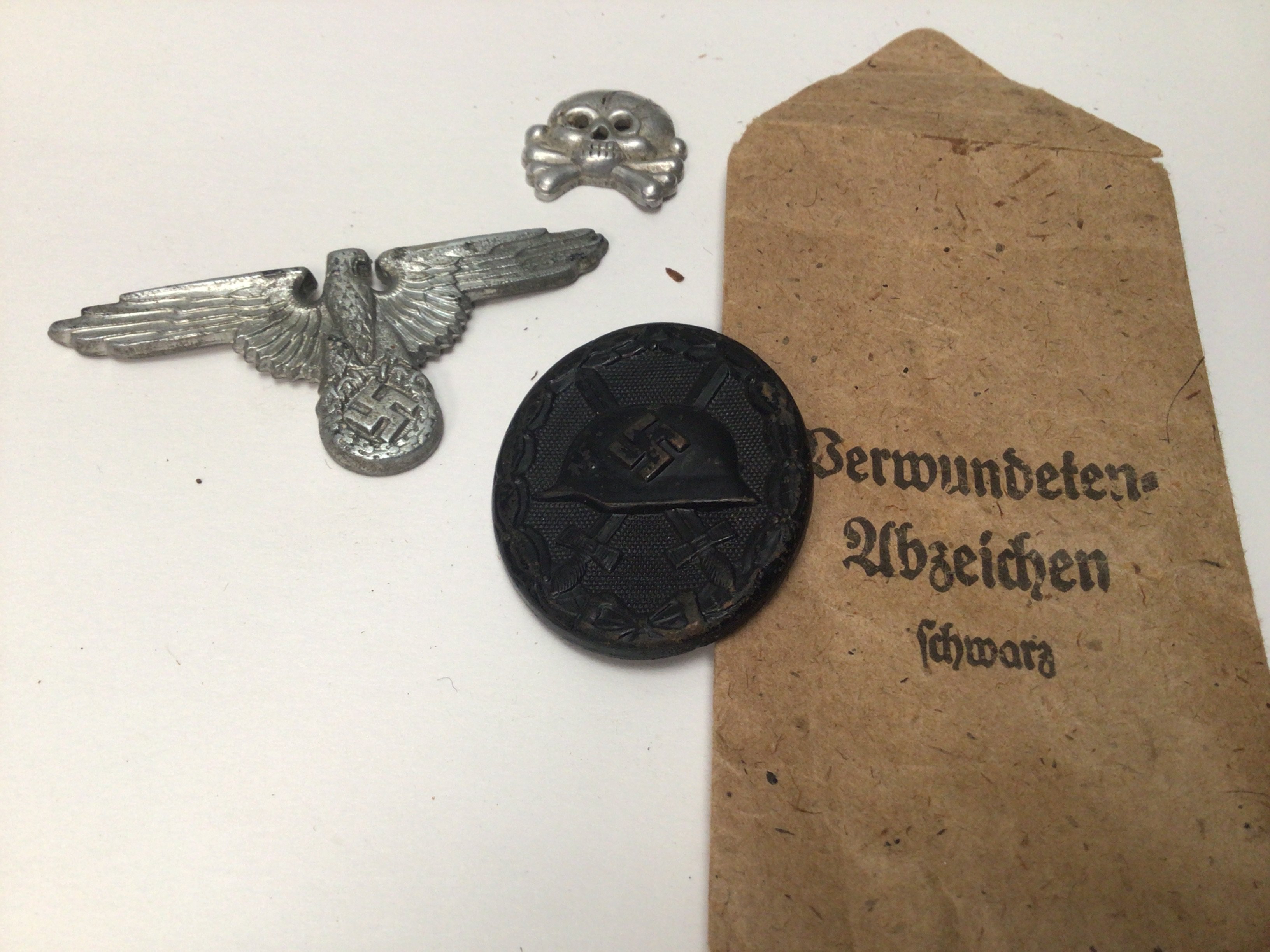 A German Third Reich Wound badge black finish reverse stamped 107 in original envelope an SS cap badge and Panzer badge (3)