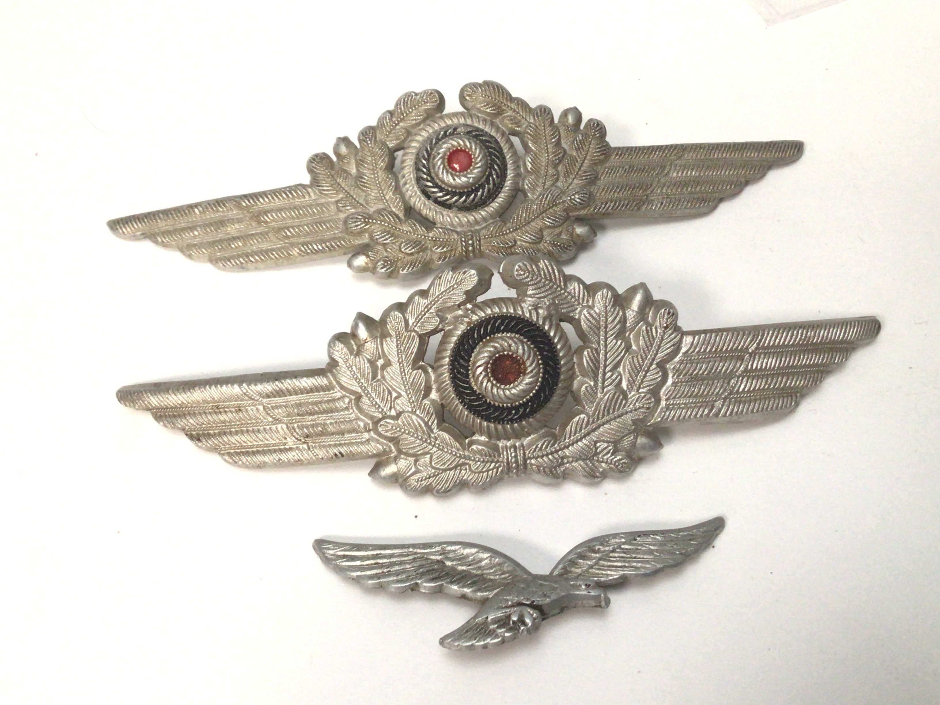 Two German Third Reich Luftwaffe peaked cap officers Insignia one other conforming badge. (3)