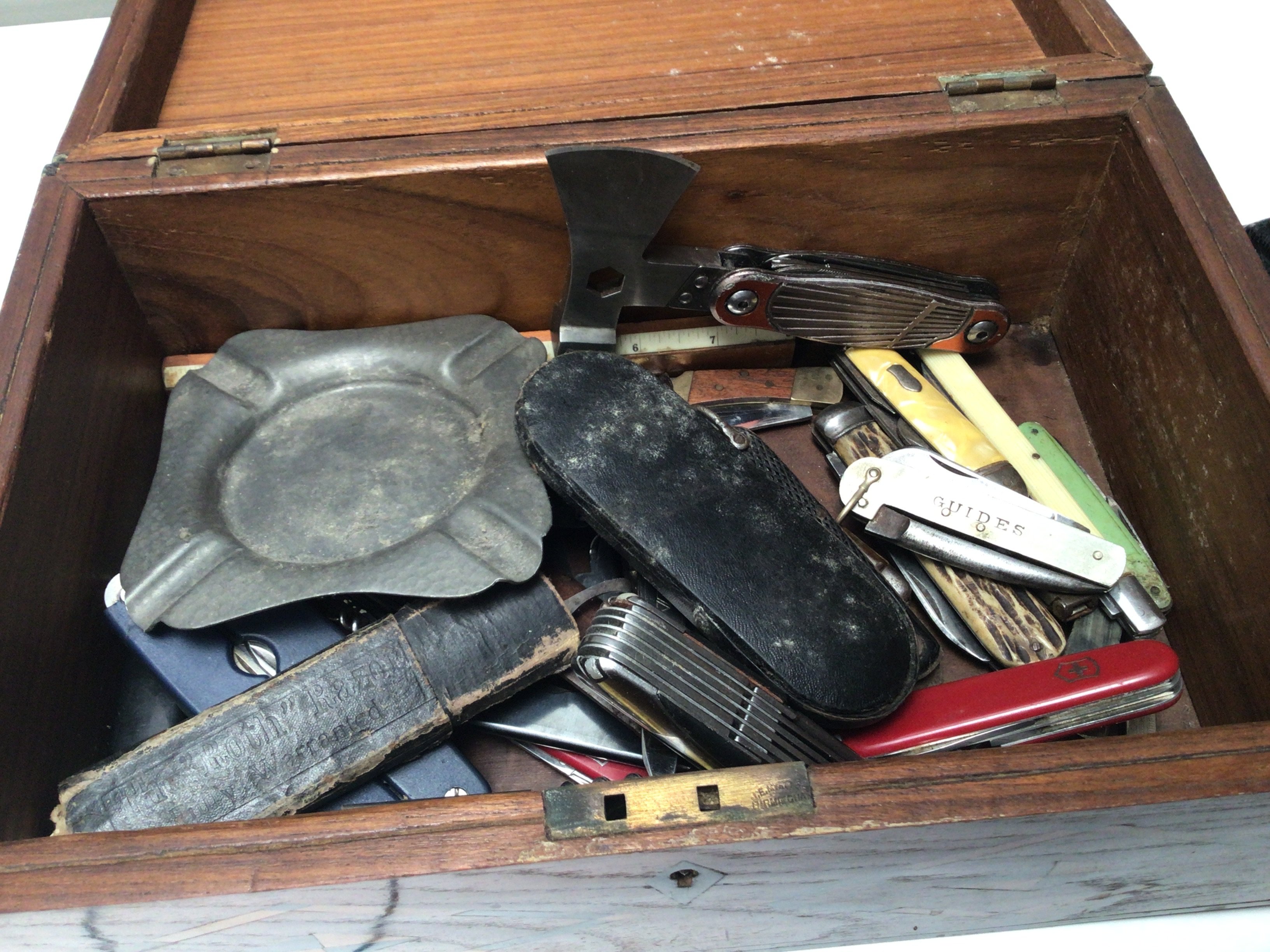 An inlaid box containing Swiss Army type folding knifes advertising Gordon&rsquo;s cork screws and others.