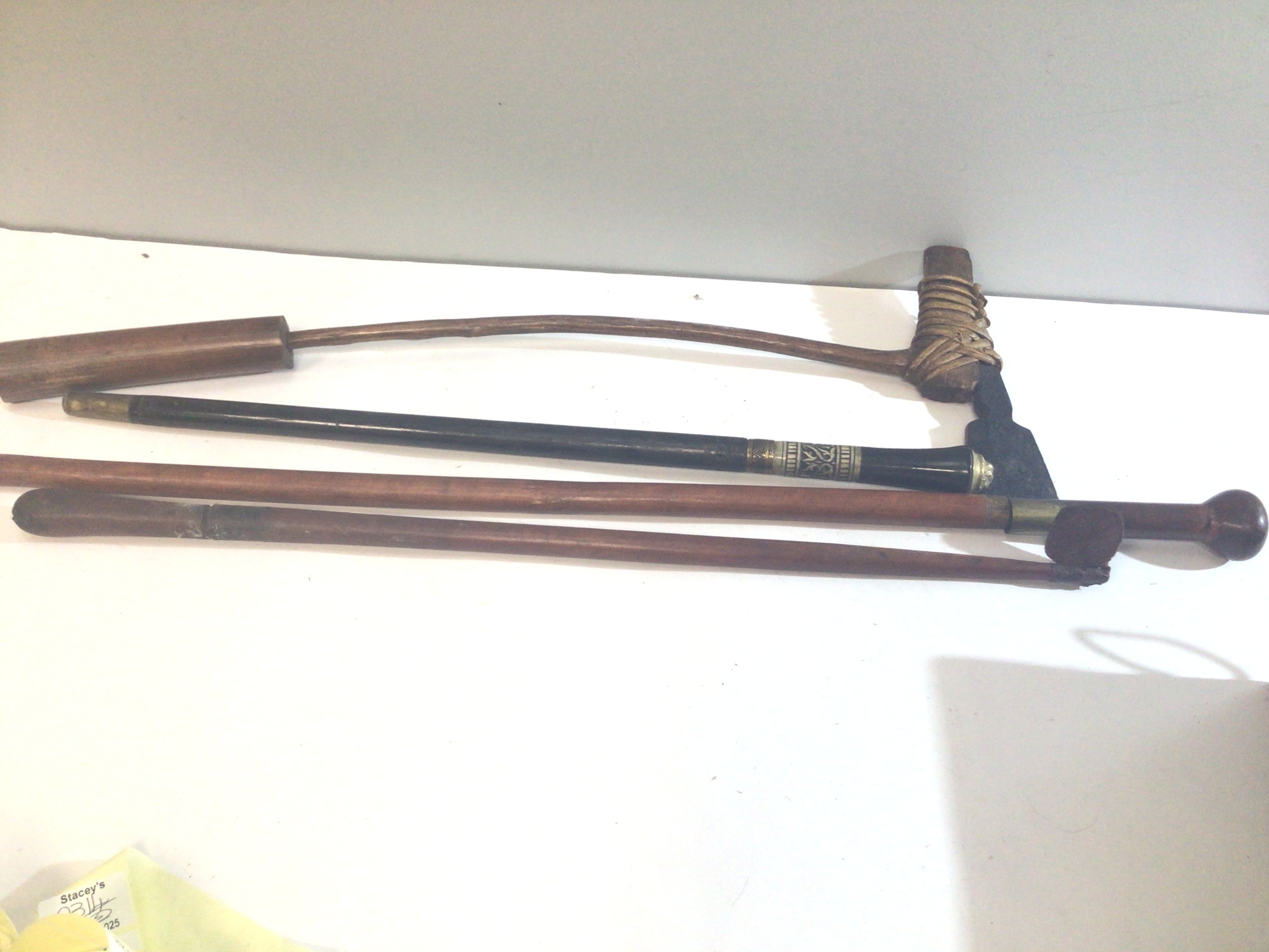 An Indian ebony sword stick two other sword sticks and an unusual bamboo and tribal axe. (4)