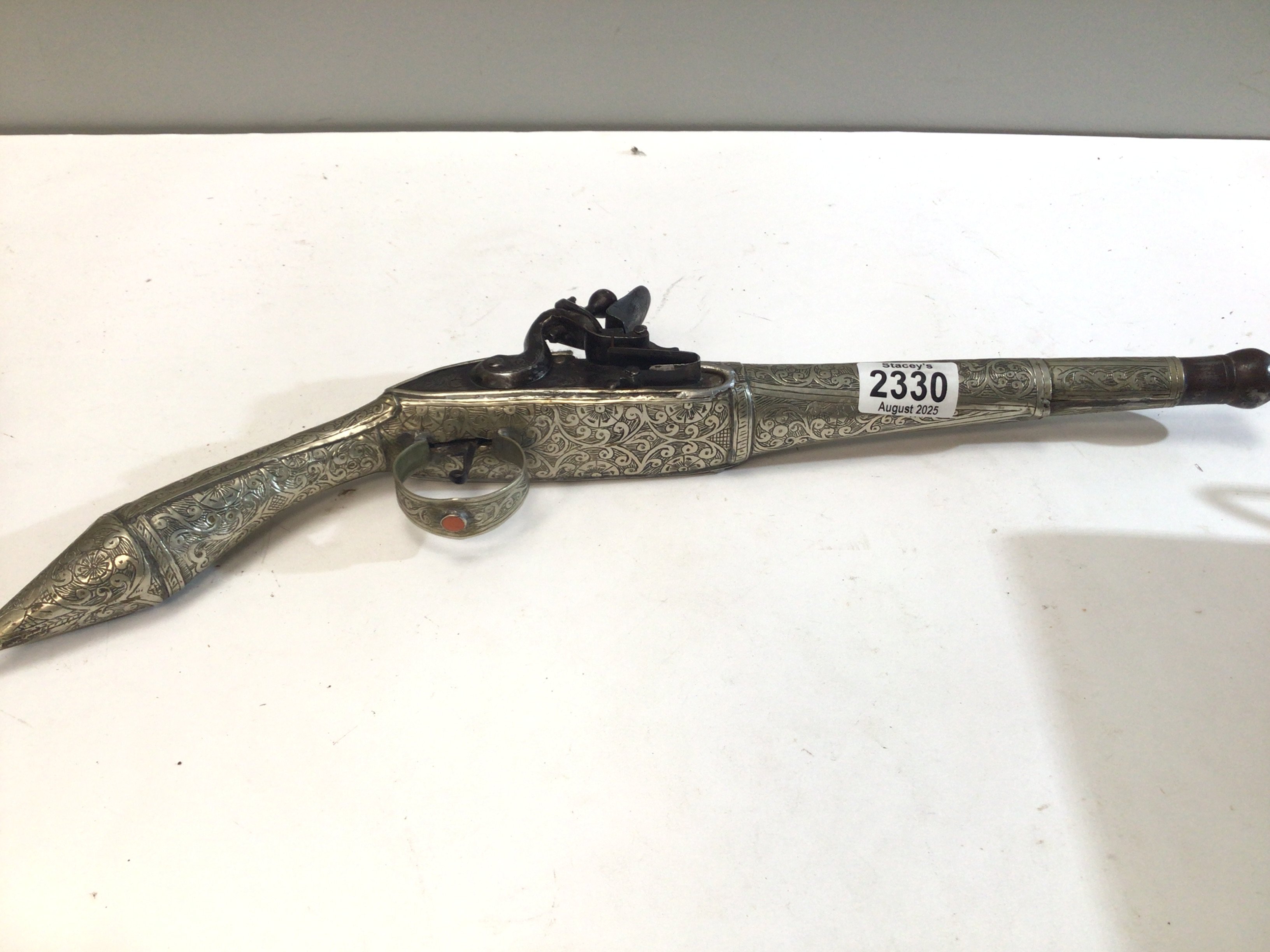 A late 18th or early 19th century Middle Eastern flintlock pistol with elaborate applied white metal decoration set with polished stone steel action. length 47cm