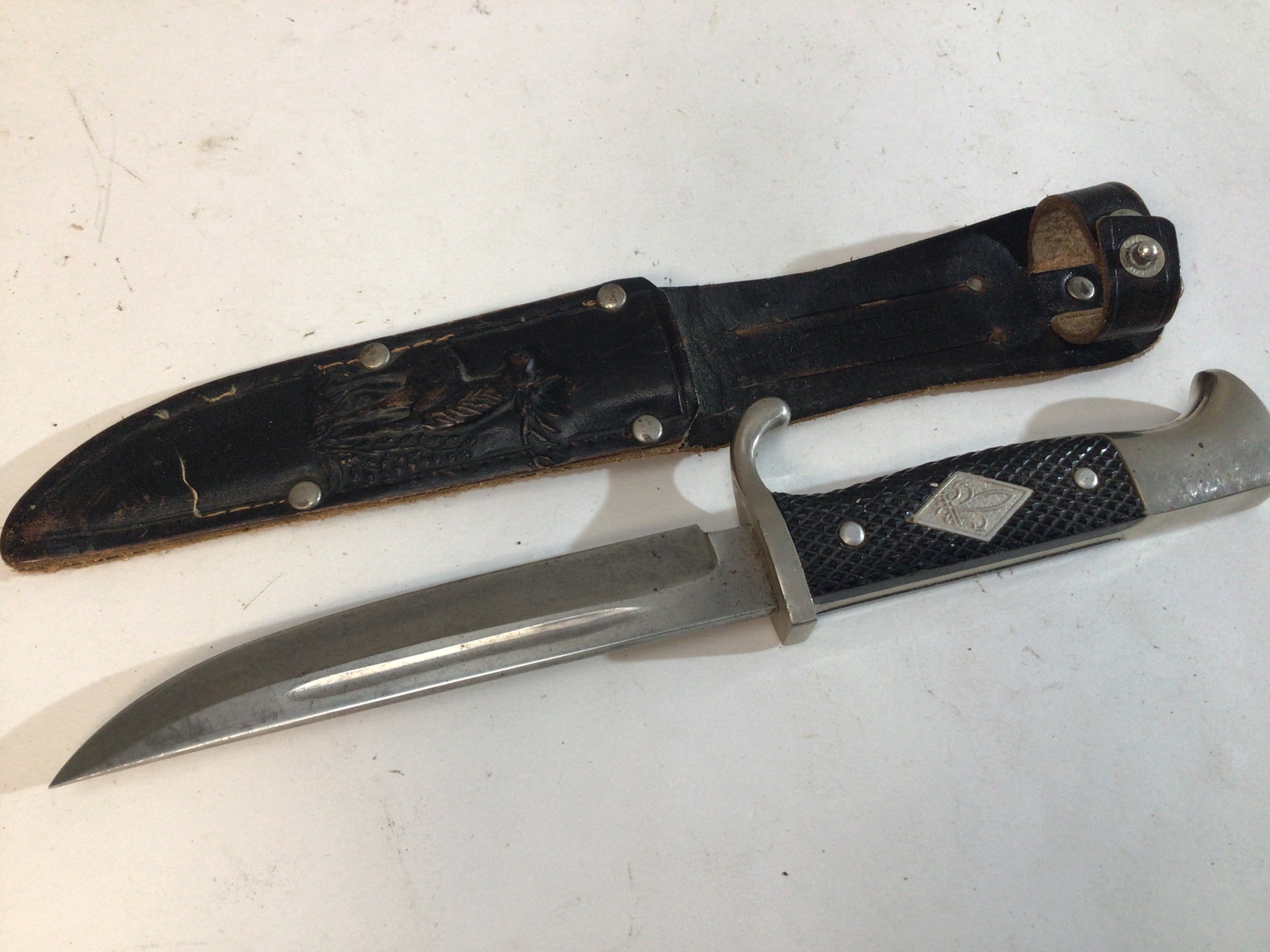 A German Scout knife the leather scabbard decorated with an image of a raised deer blade with makers name Whitey Solingen