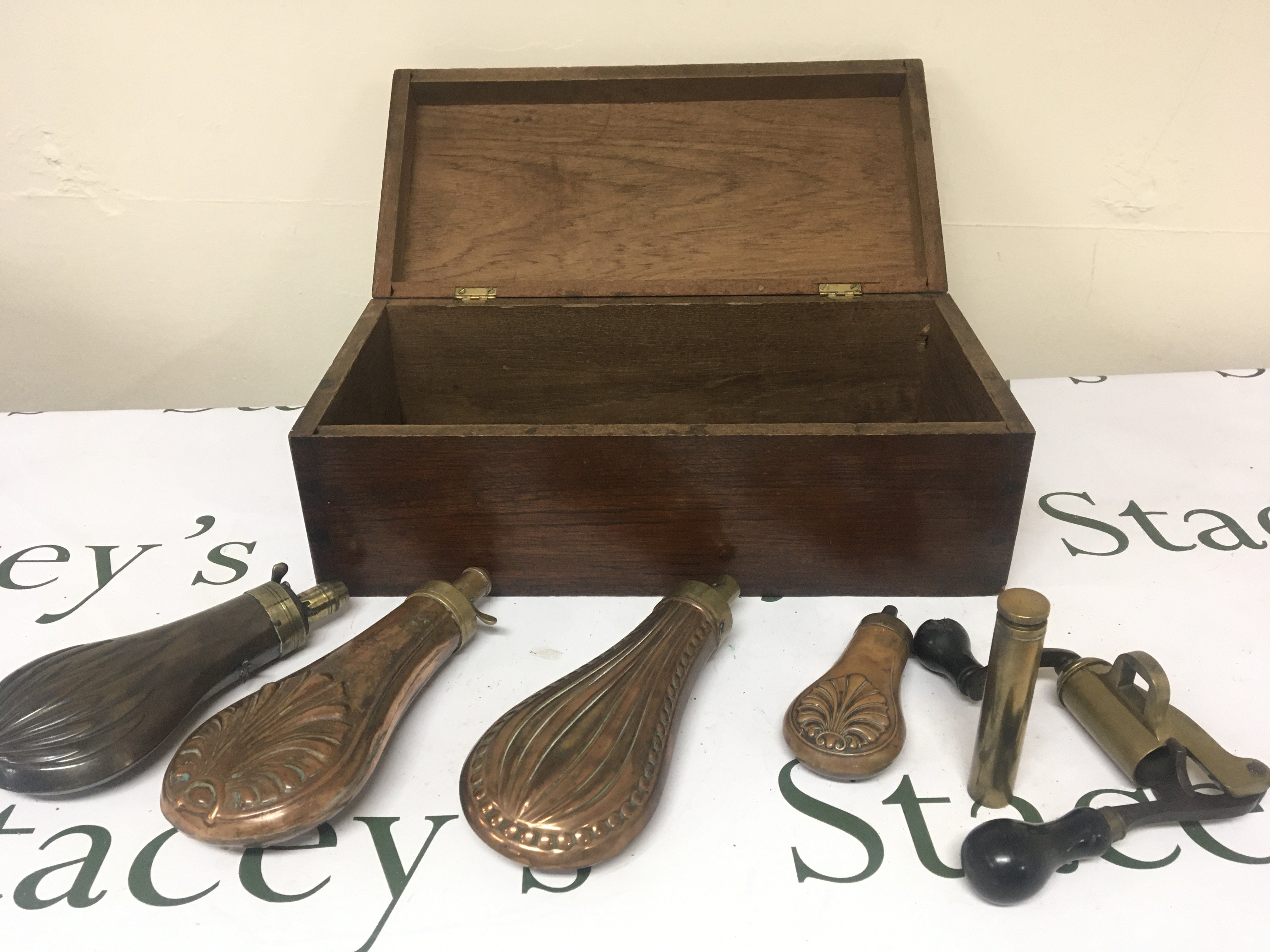 Four 19th century Copper powder flasks and cartridge loader all in a mahogany box.