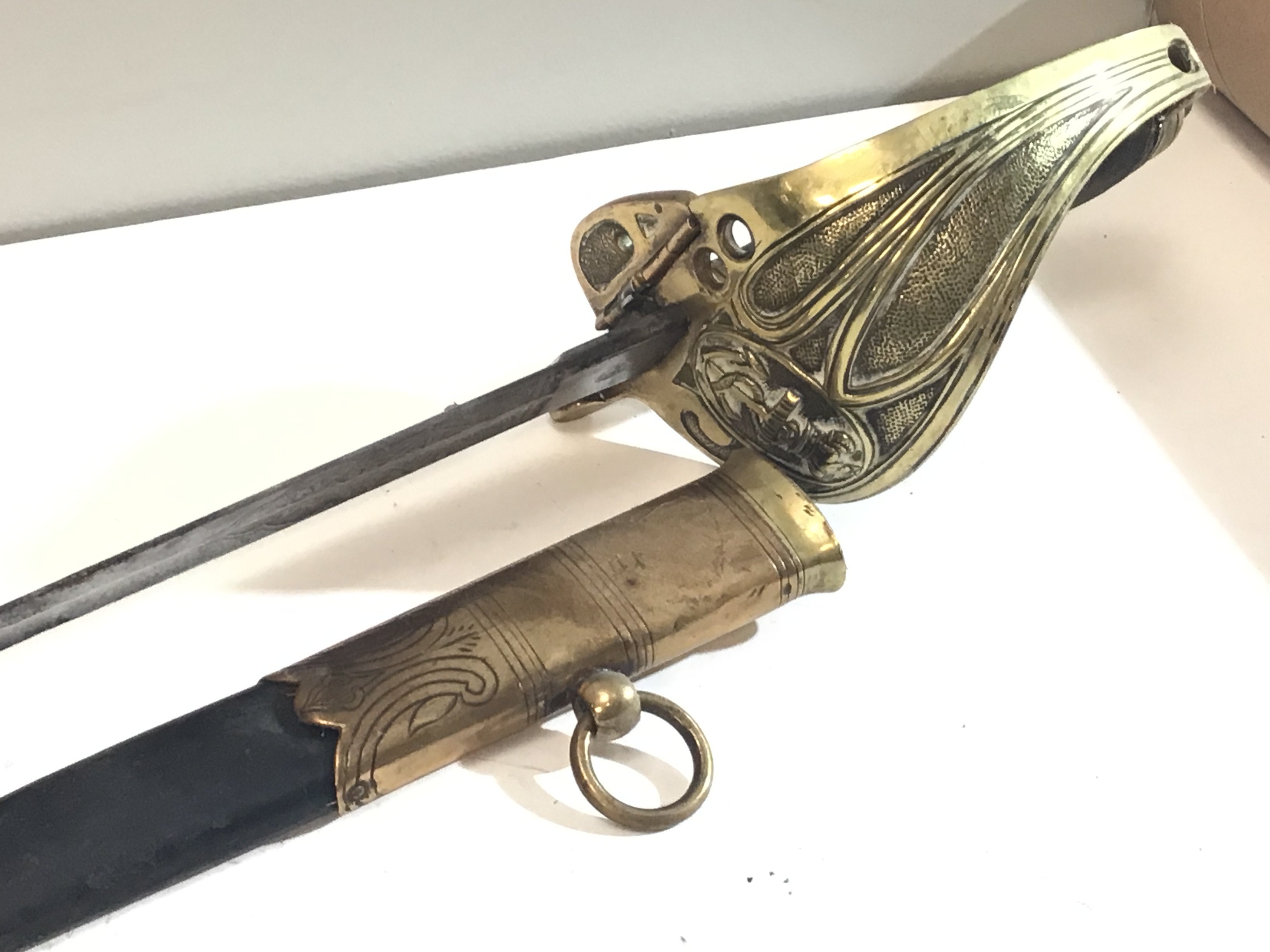 An 1827 pattern Victorian Royal British Navy Sword with a wired dark shagreen grip with brass guard with anchor and crown etched blade with further conforming decoration. Leather and brass scabbard.